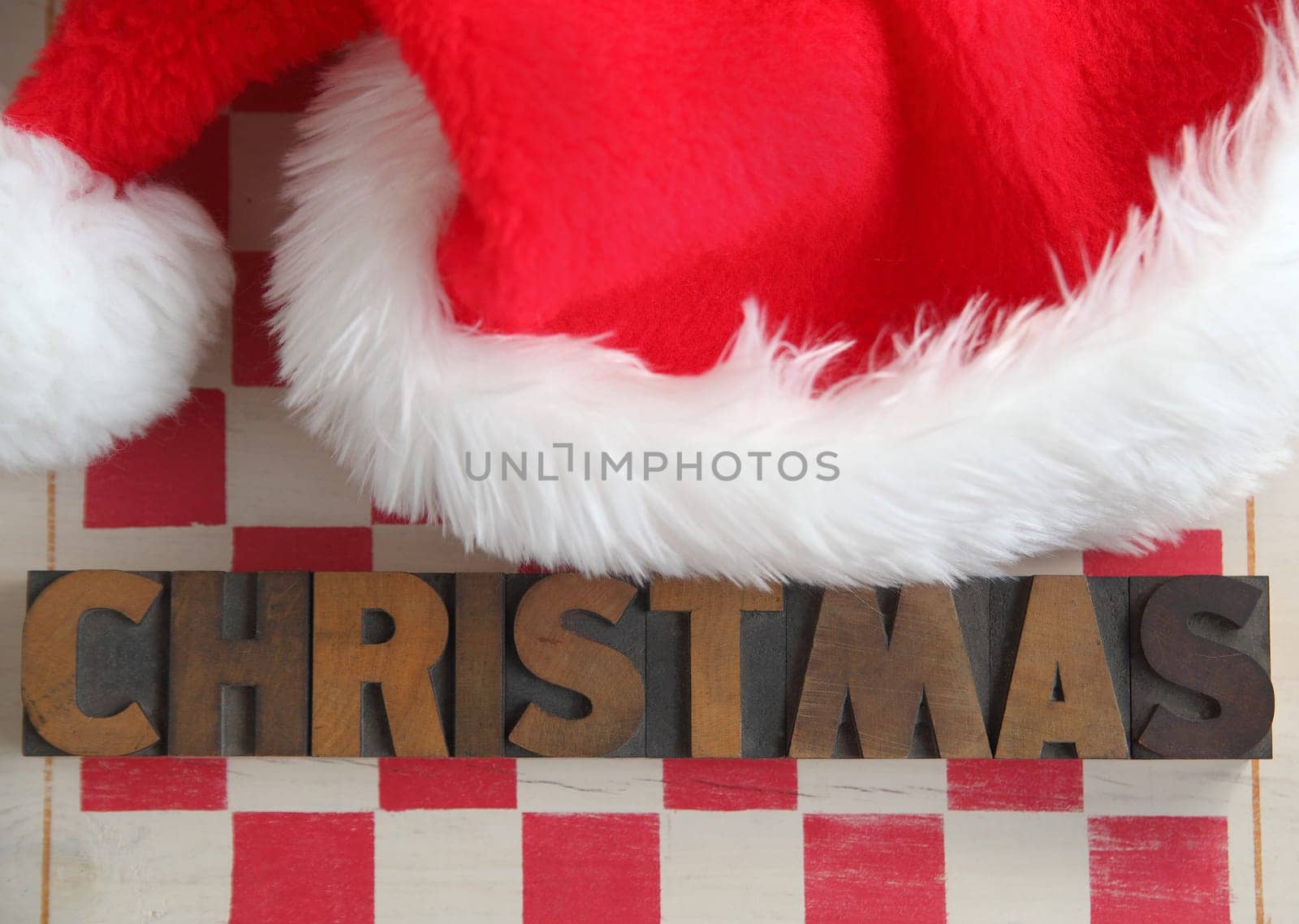 Santa hat on stenciled checkerboard with the word 'Christmas' in old wood type