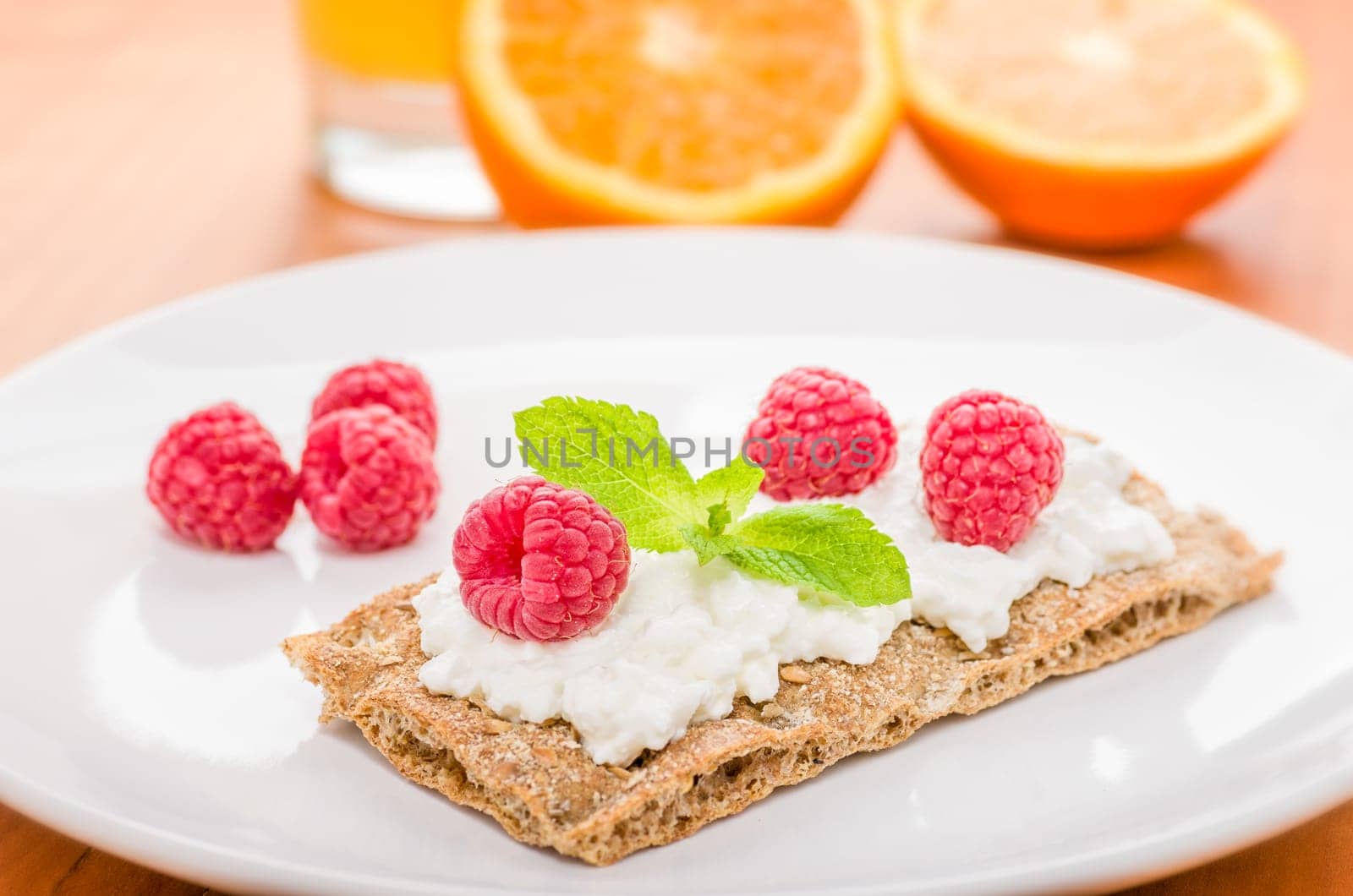 Crispbread with cream cheese and raspberries on a set breakfast table