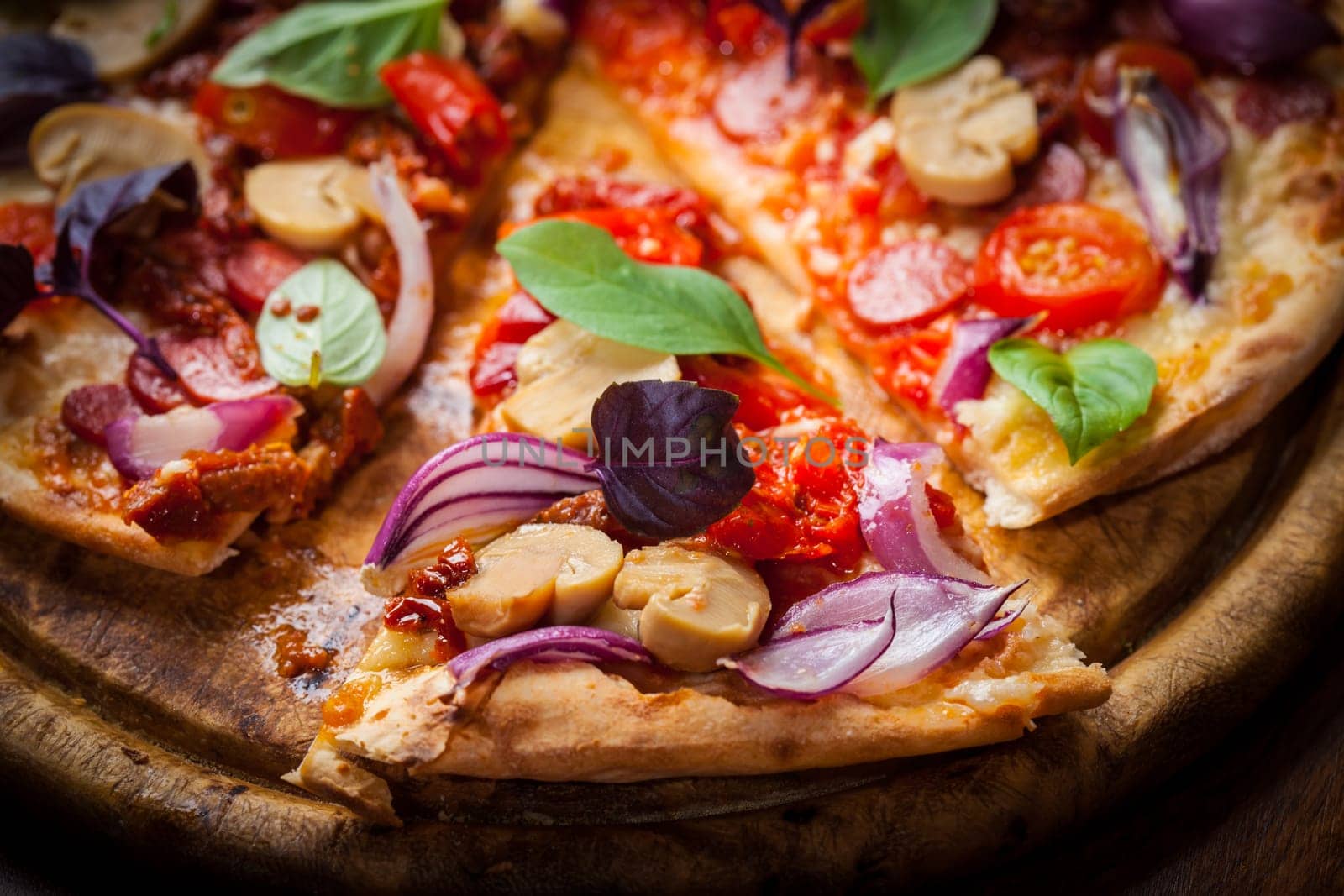 Homemade pizza with dried tomatoes, salami and basil