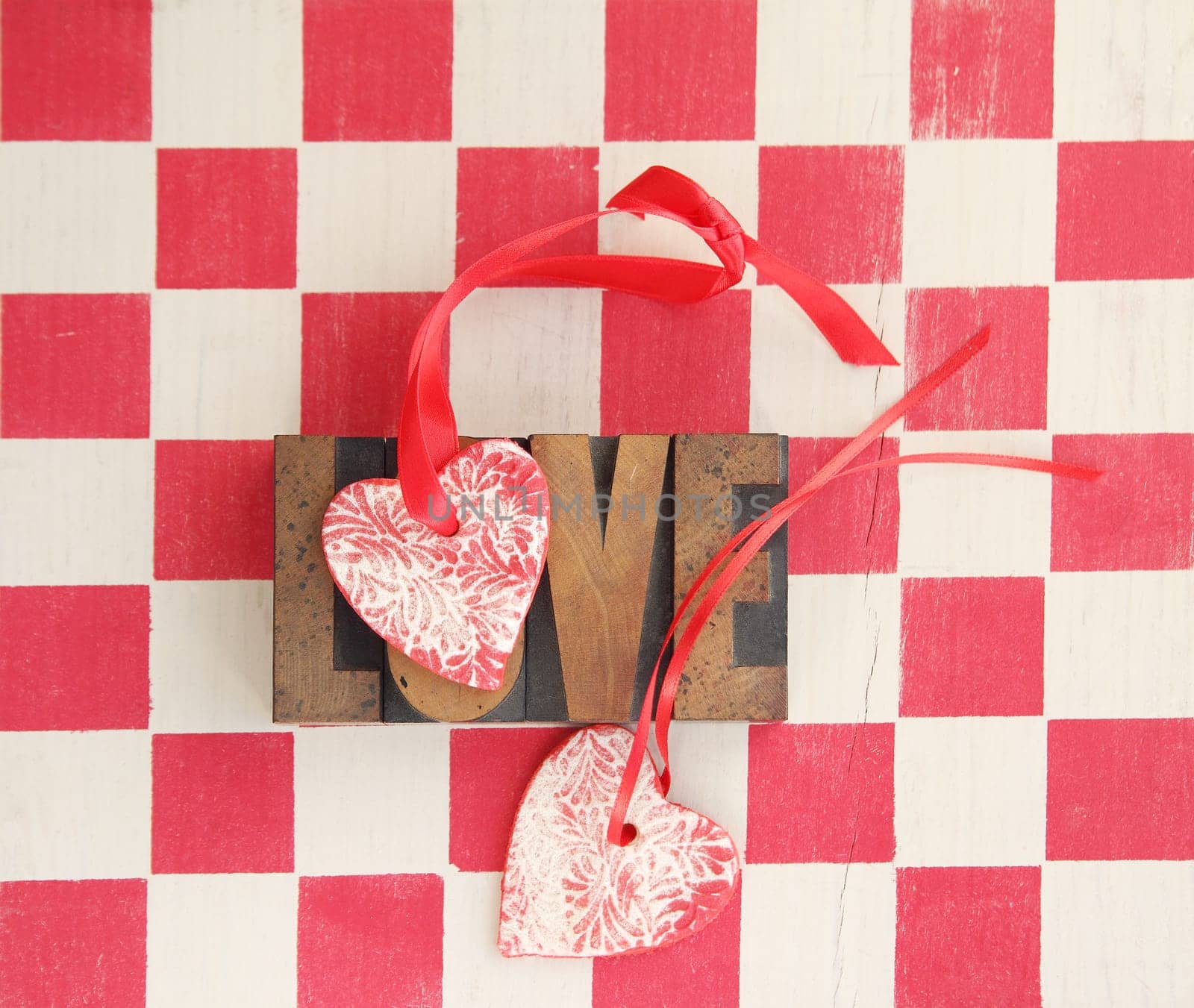 the word love repeated three times with a handmade heart ornament on a checkerboard