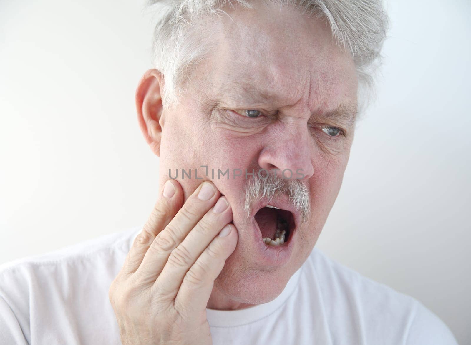 senior man with hand on his painful cheek