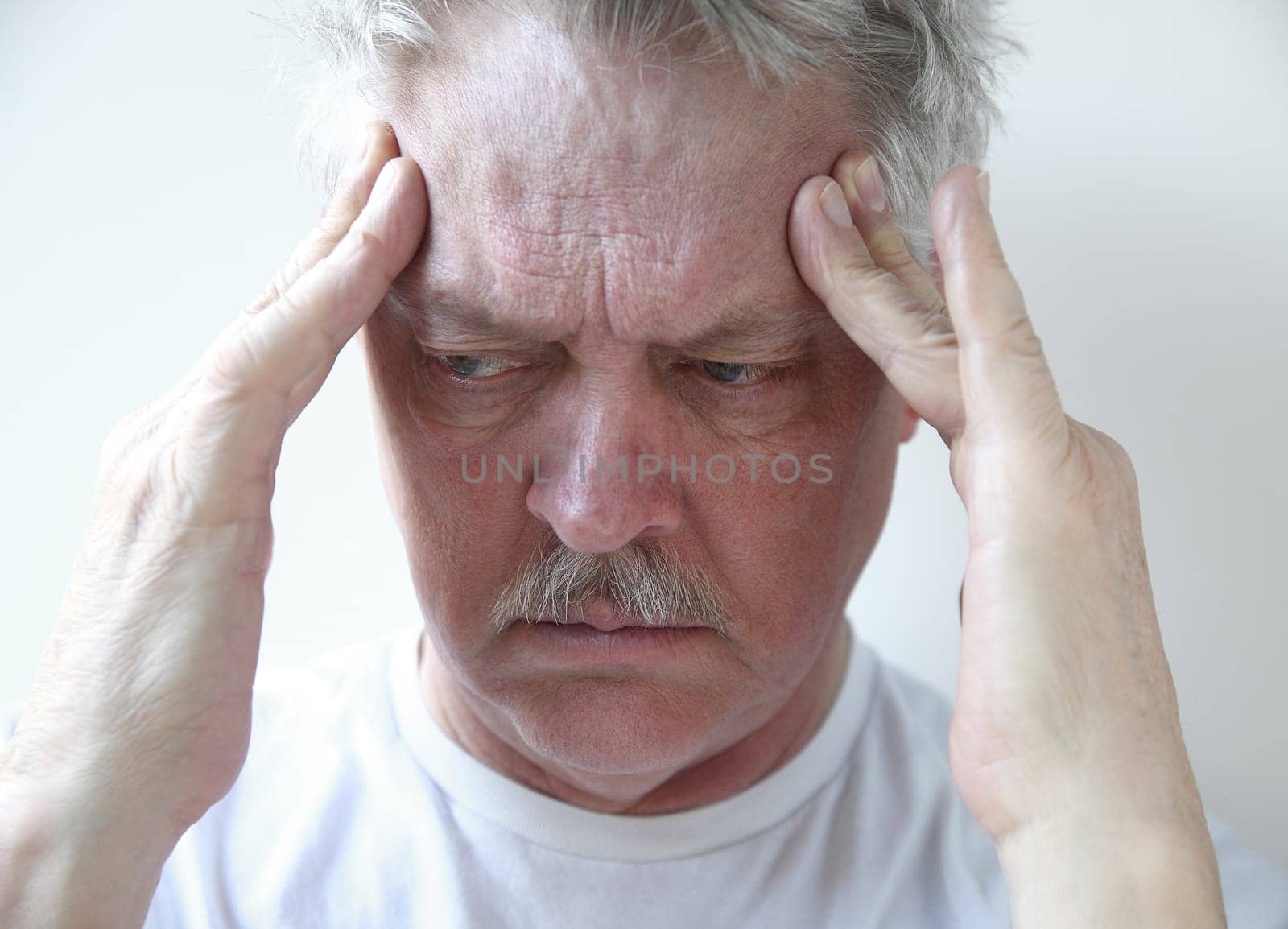 senior man with fingers on his throbbing headache pain