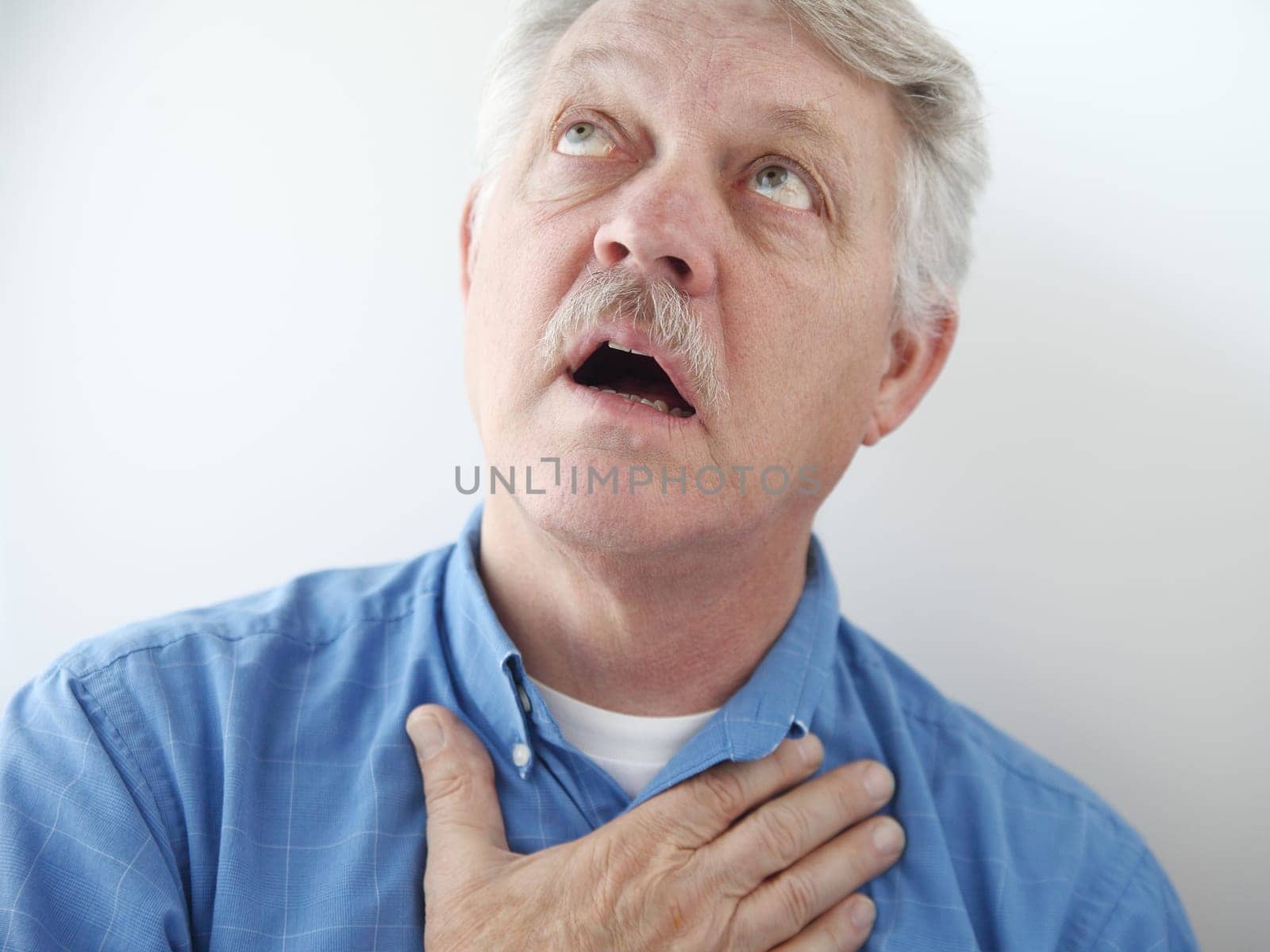 older man gazes skyward with a hand on his chest