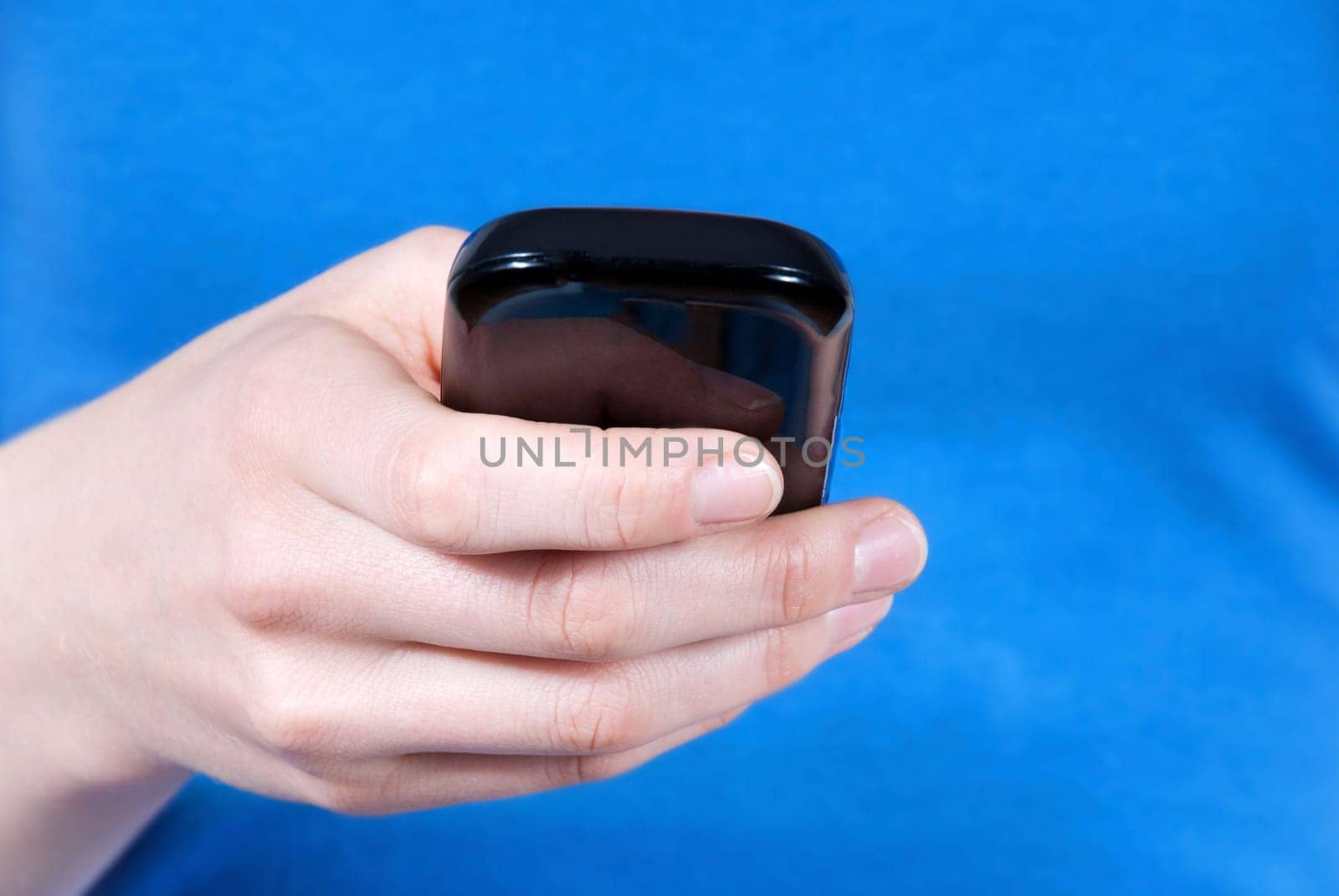 a hand using a smartphone in front of its body, blue background