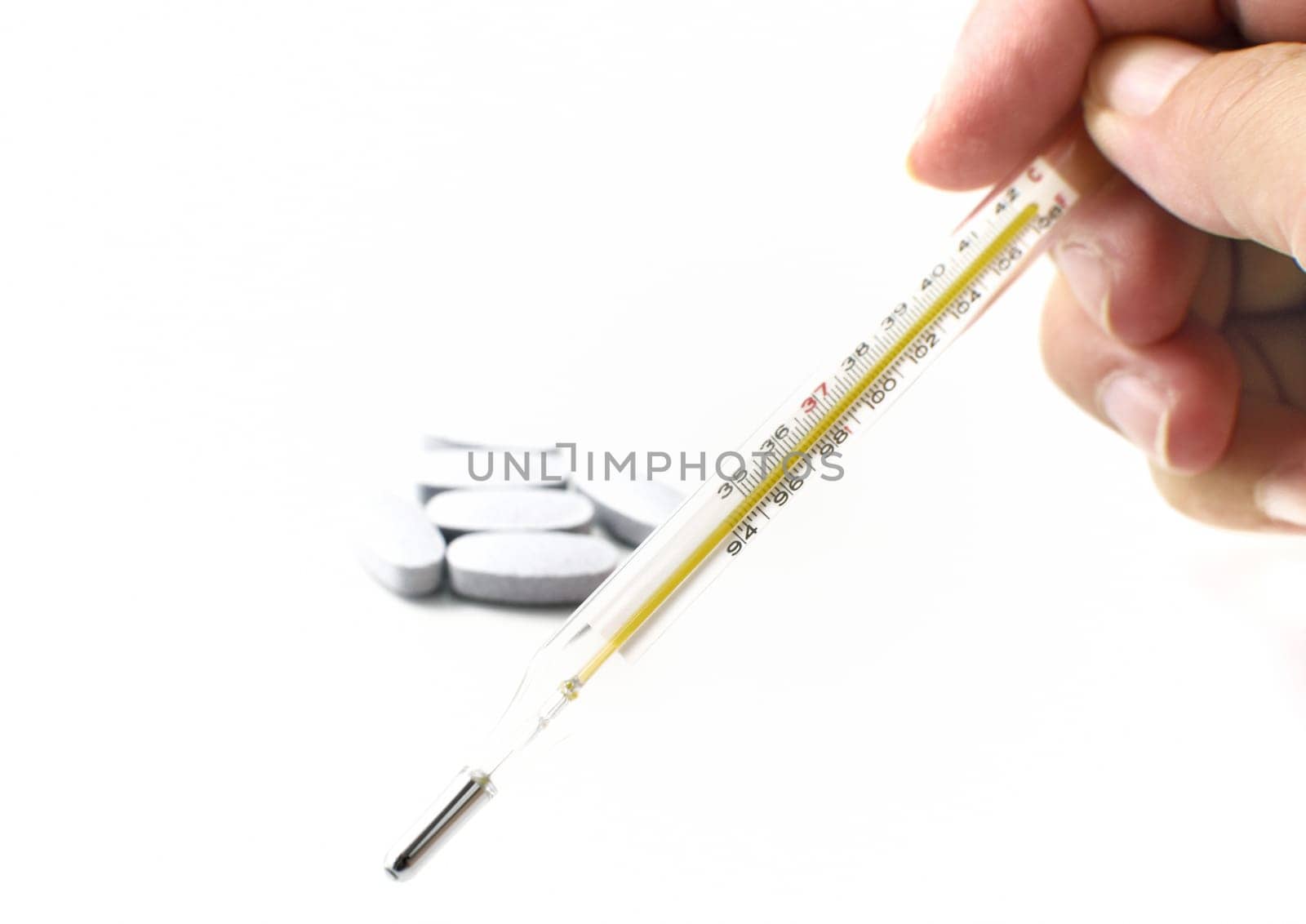 Thermometer and pills on white background