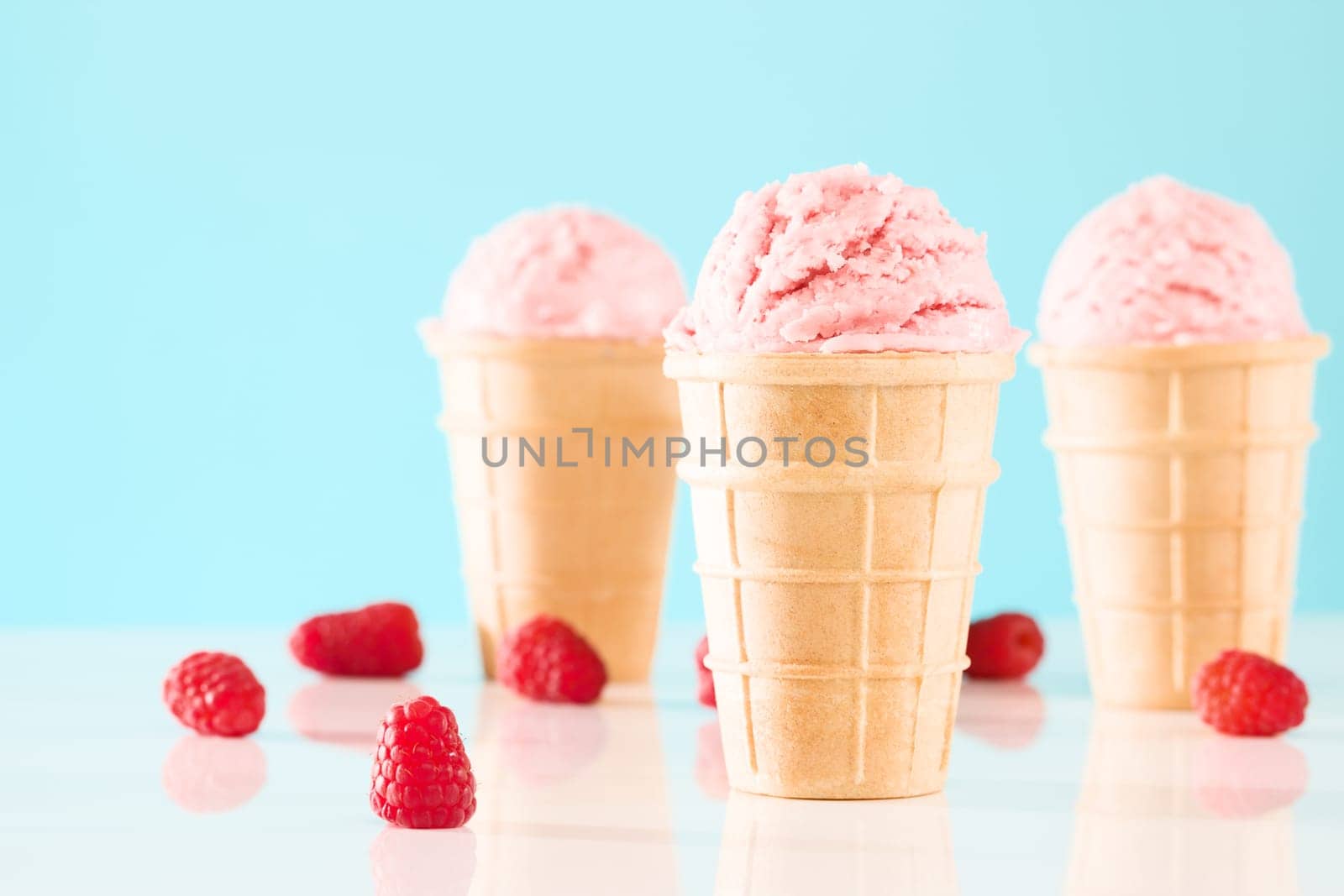 Raspberries ice cream in waffles against blue background