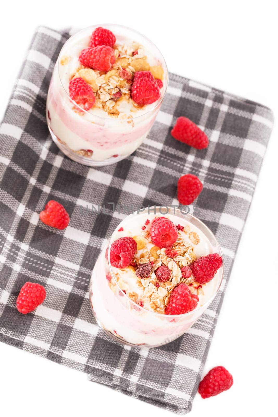 Muesli desserts with raspberries on a tea towel from above