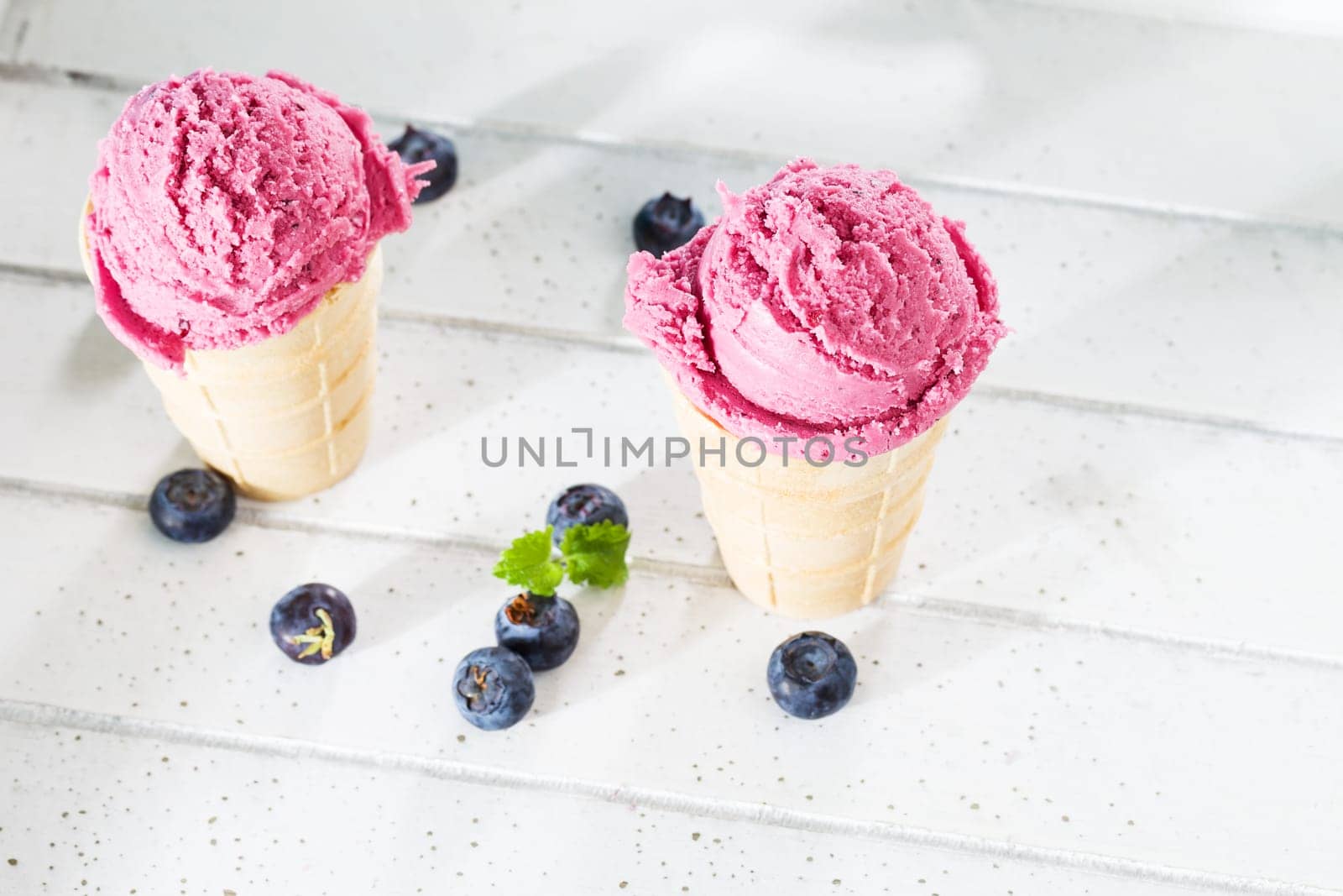 Blueberry ice cream from above on white wood with blueberries