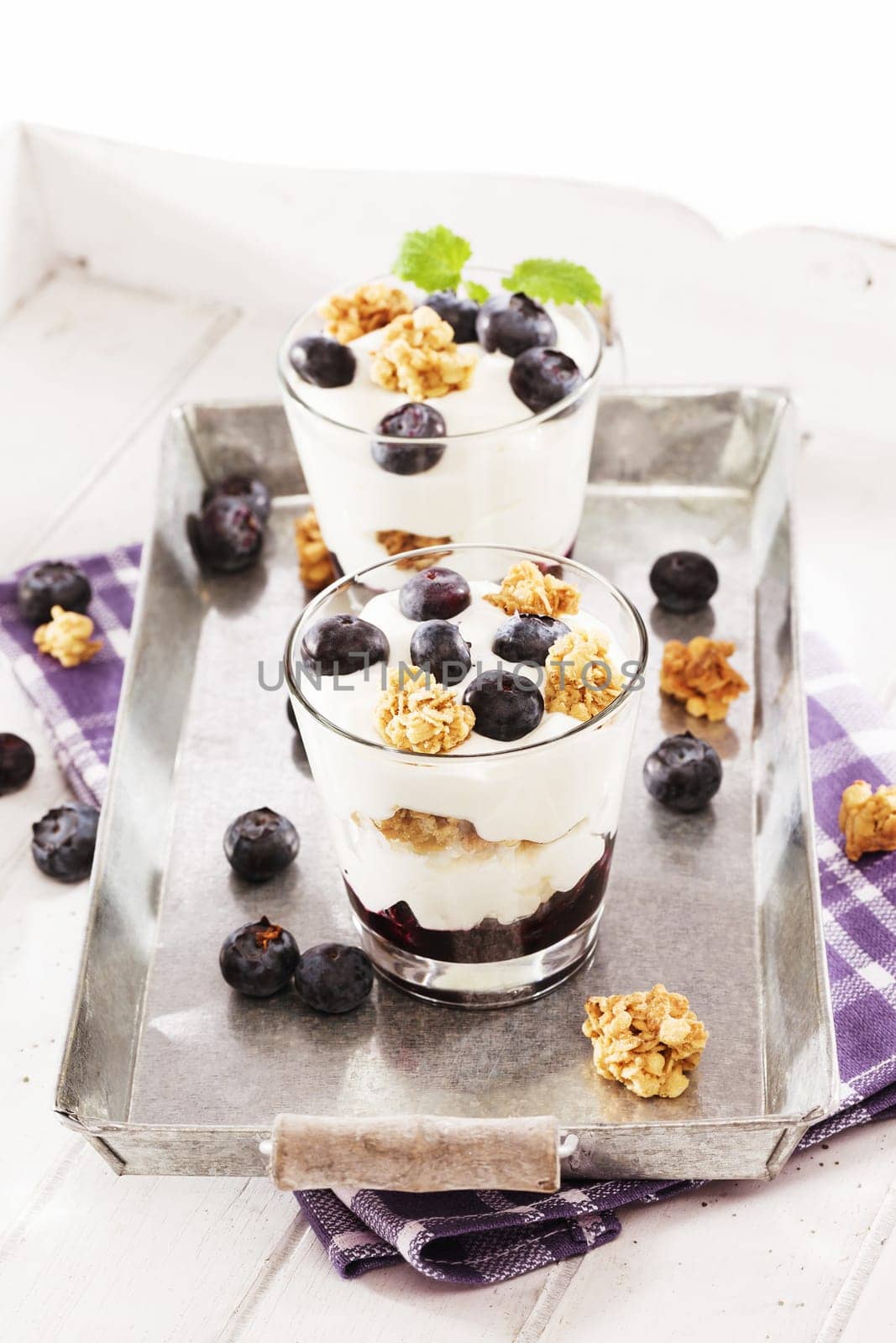 Desserts with yogurt and blueberries on metal with tea towel