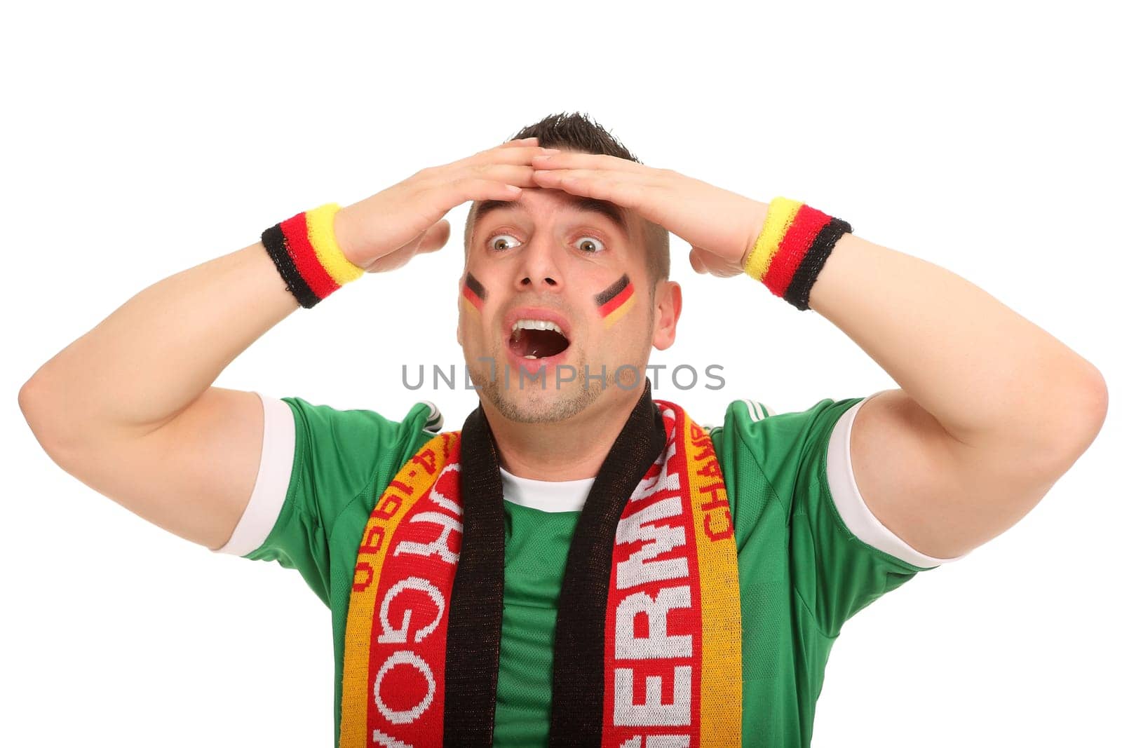 A football fan stands there and has a helpless expression. He touches his head with his hands.