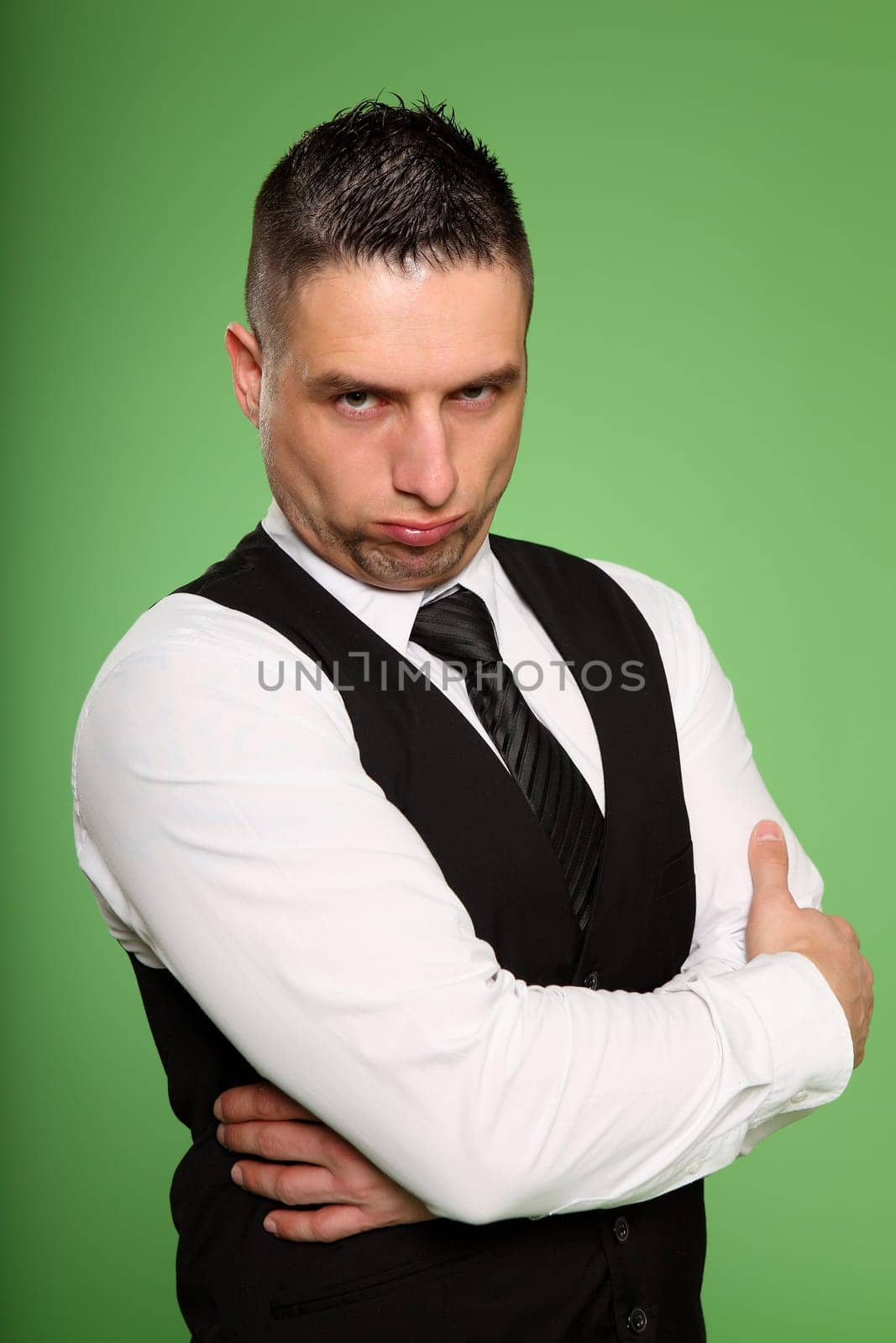 The photo shows a businessman standing very stubbornly in front of the camera with his arms crossed.