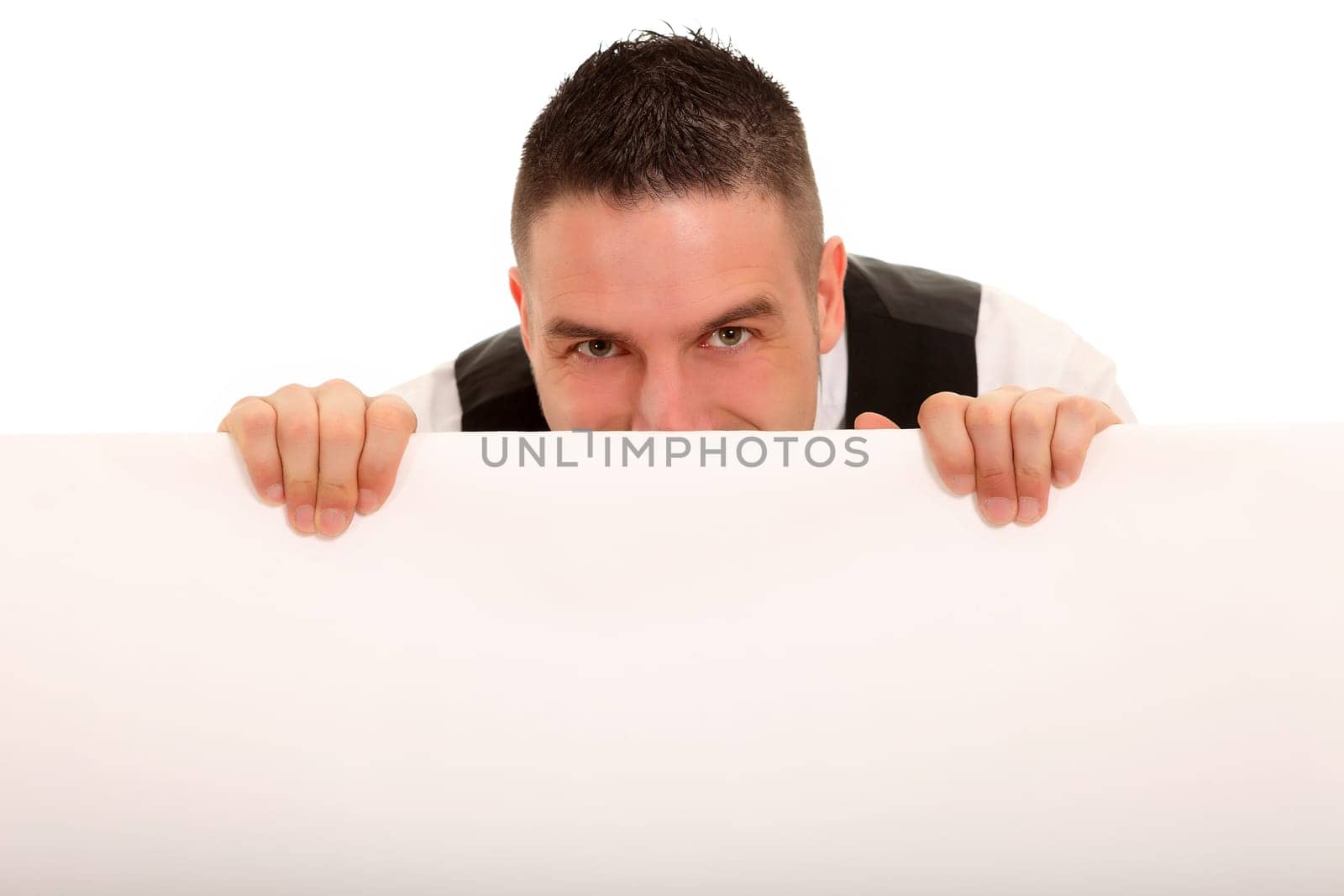 A young man hides behind an advertising sign and looks friendly
