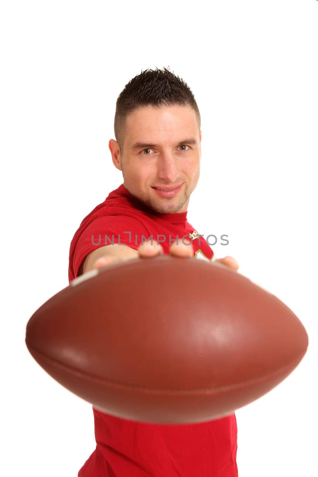 A young man holds an American football directly in front of the camera and smiles