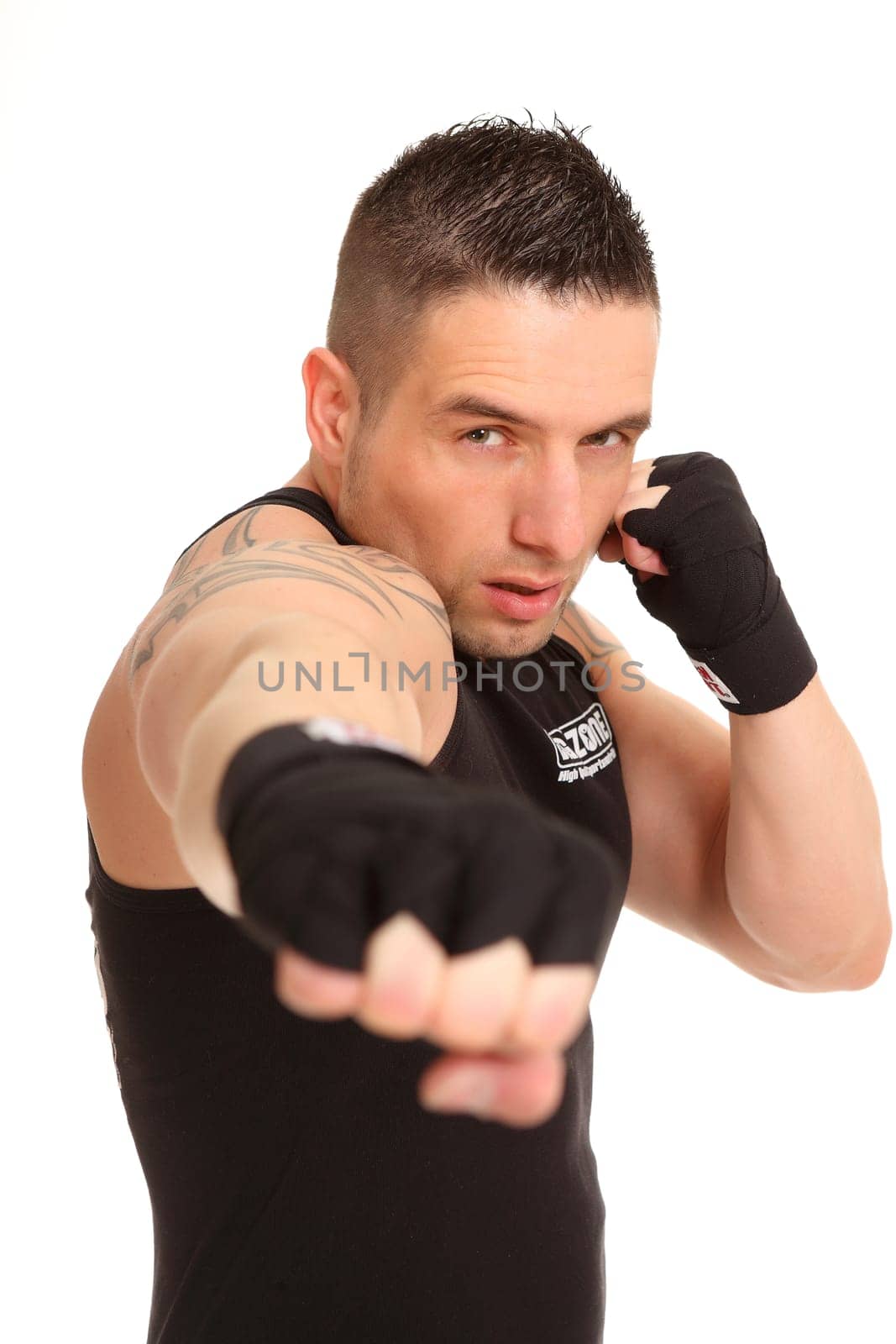 The photo shows a young man wearing bandages on his hands and punching in the direction of the camera. He looks serious.