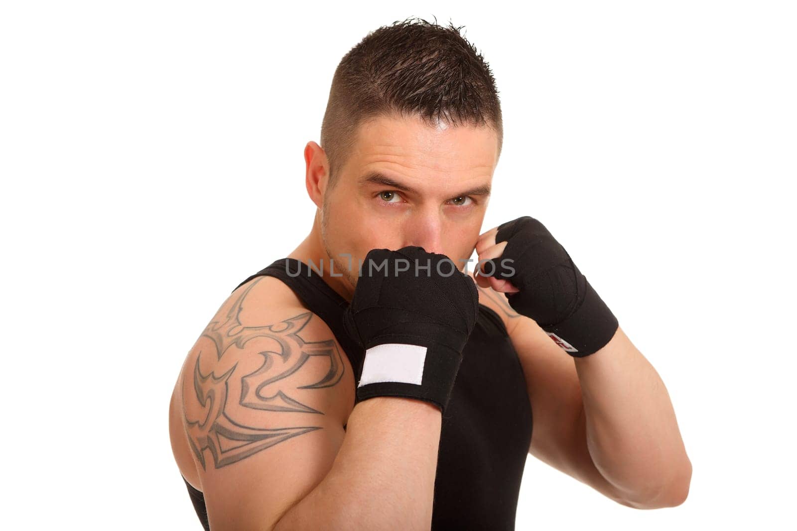 A young man stands there in a defensive boxing posture and looks into the camera with a fixed gaze