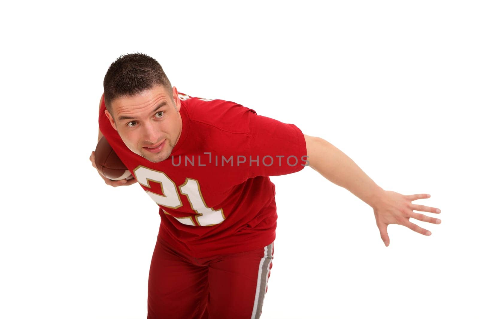 A man with a football under his arm seems to be running and looks to the side with wide eyes