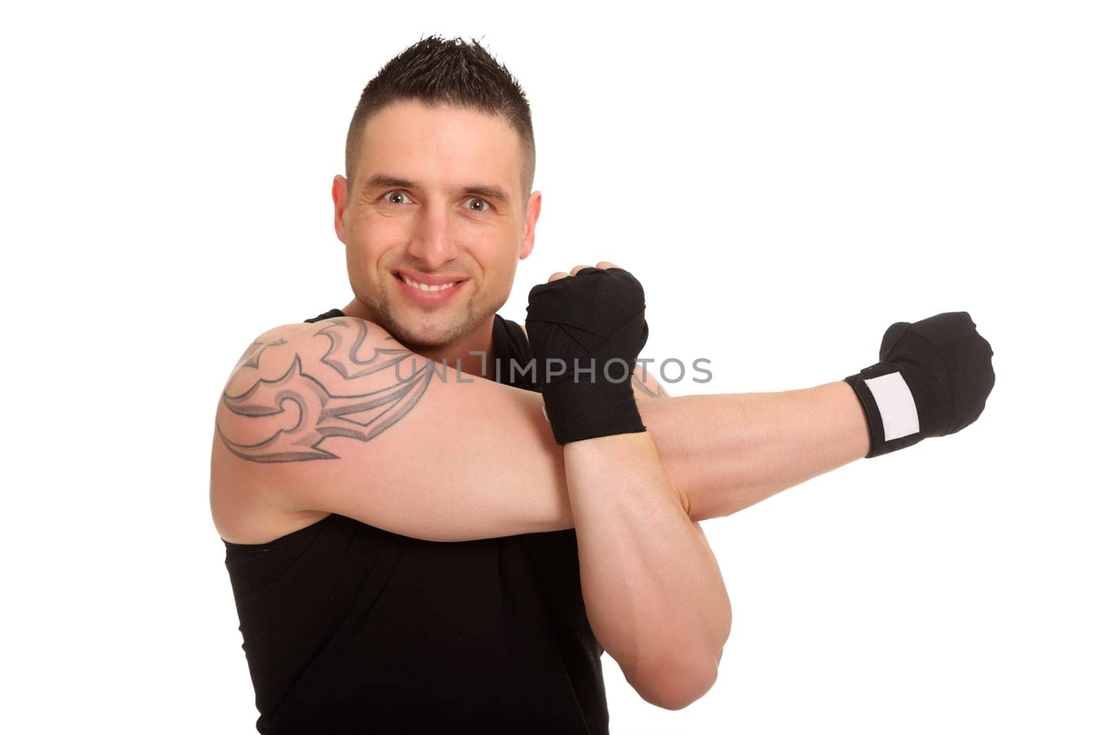 The photo shows a boxer warming up and doing a stretching exercise. He looks into the camera with a smile