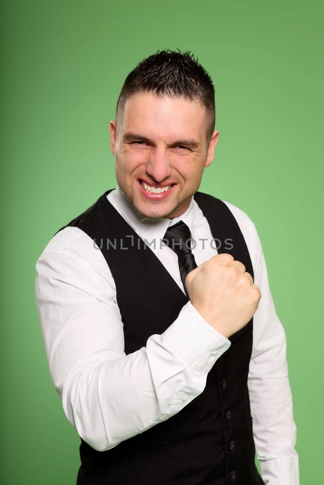A young businessman has bent one arm powerfully and looks aggressively into the camera.