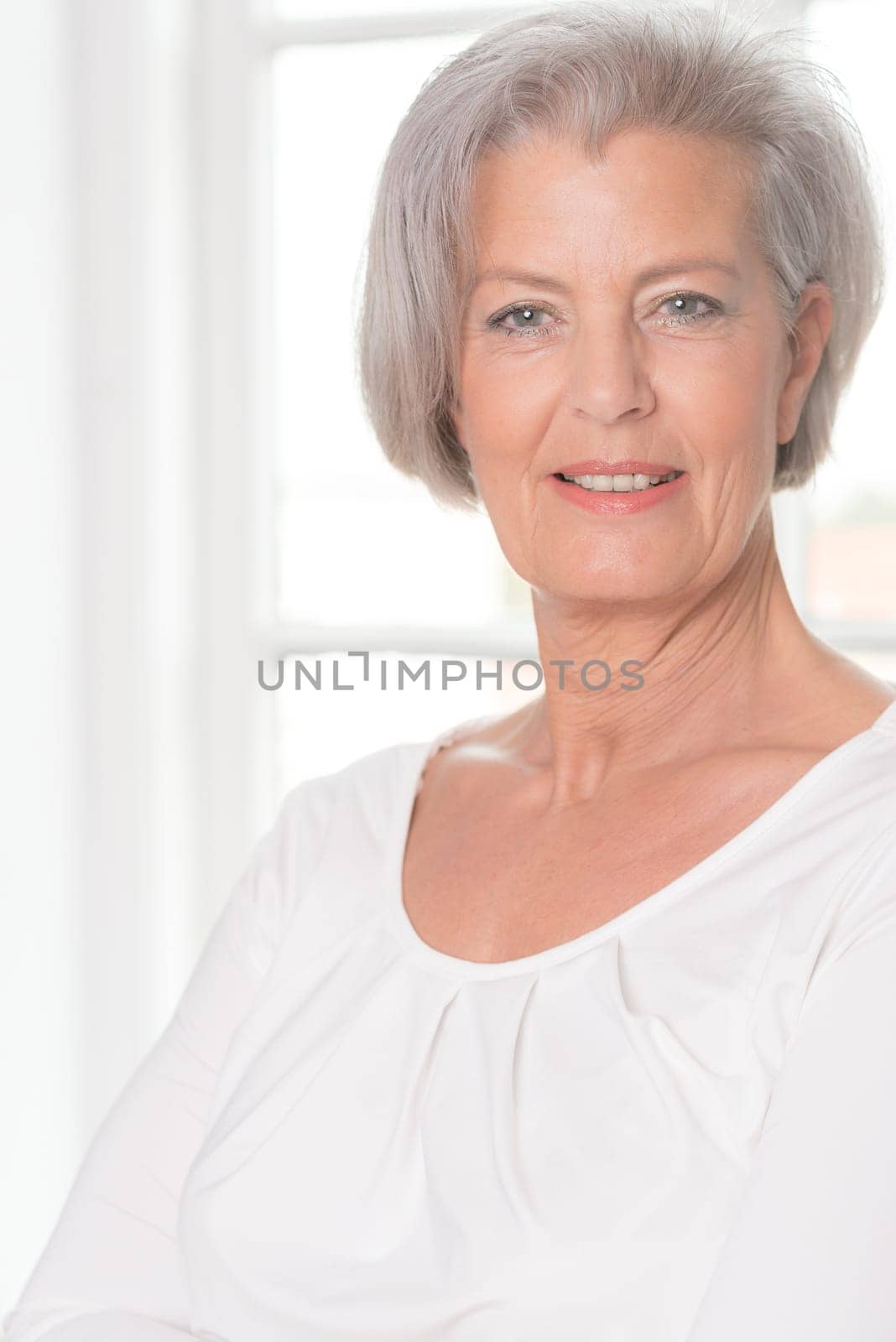 Smiling senior woman in front of a bright window