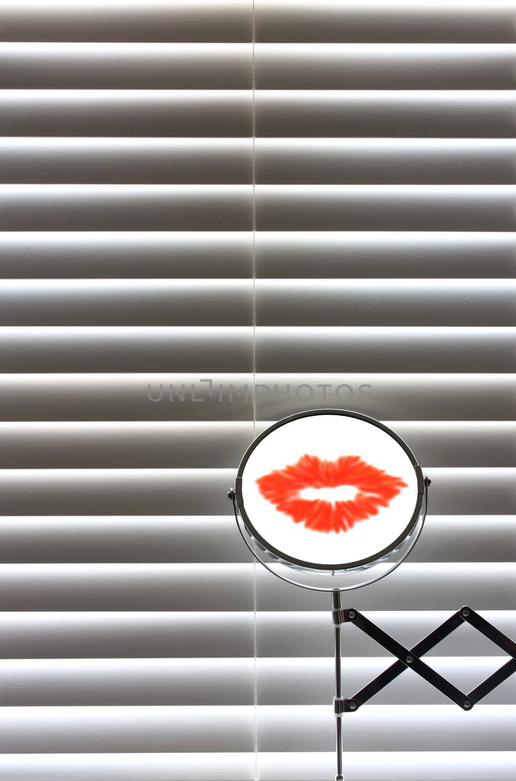 Bathroom mirror with lipstick in front of blinds with sun coming though