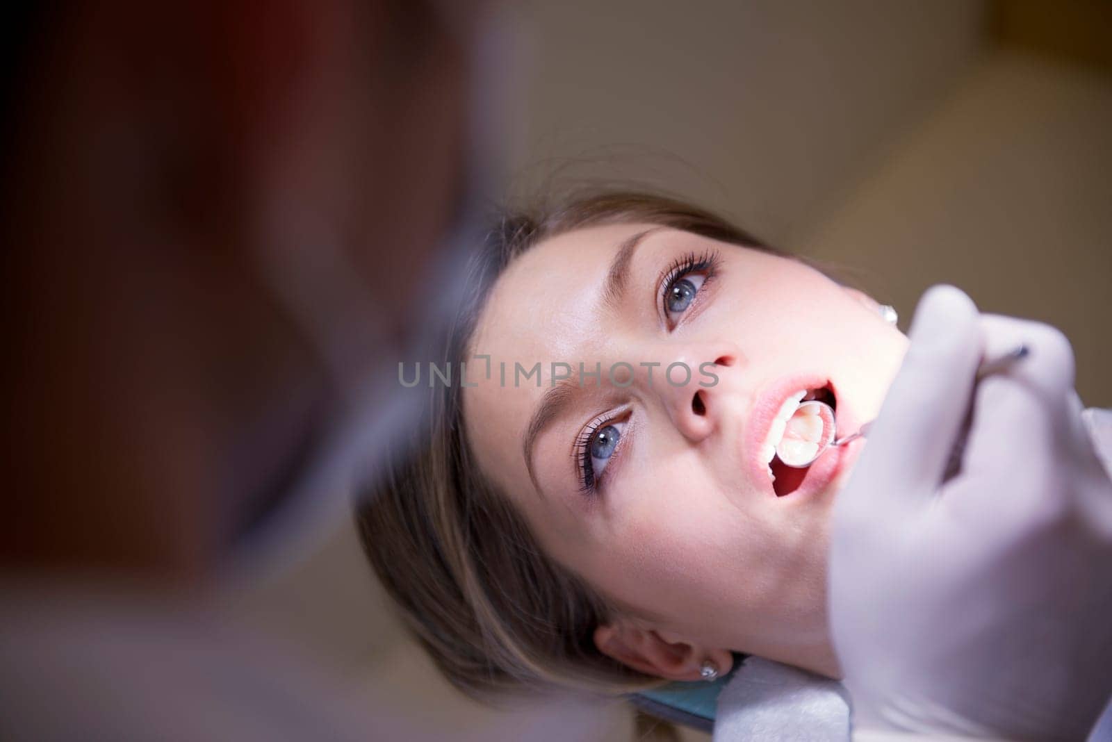 Doctor visiting patient in dental clinic, young woman lying on couch in hospital with dentist checking her teeth hygiene during exam