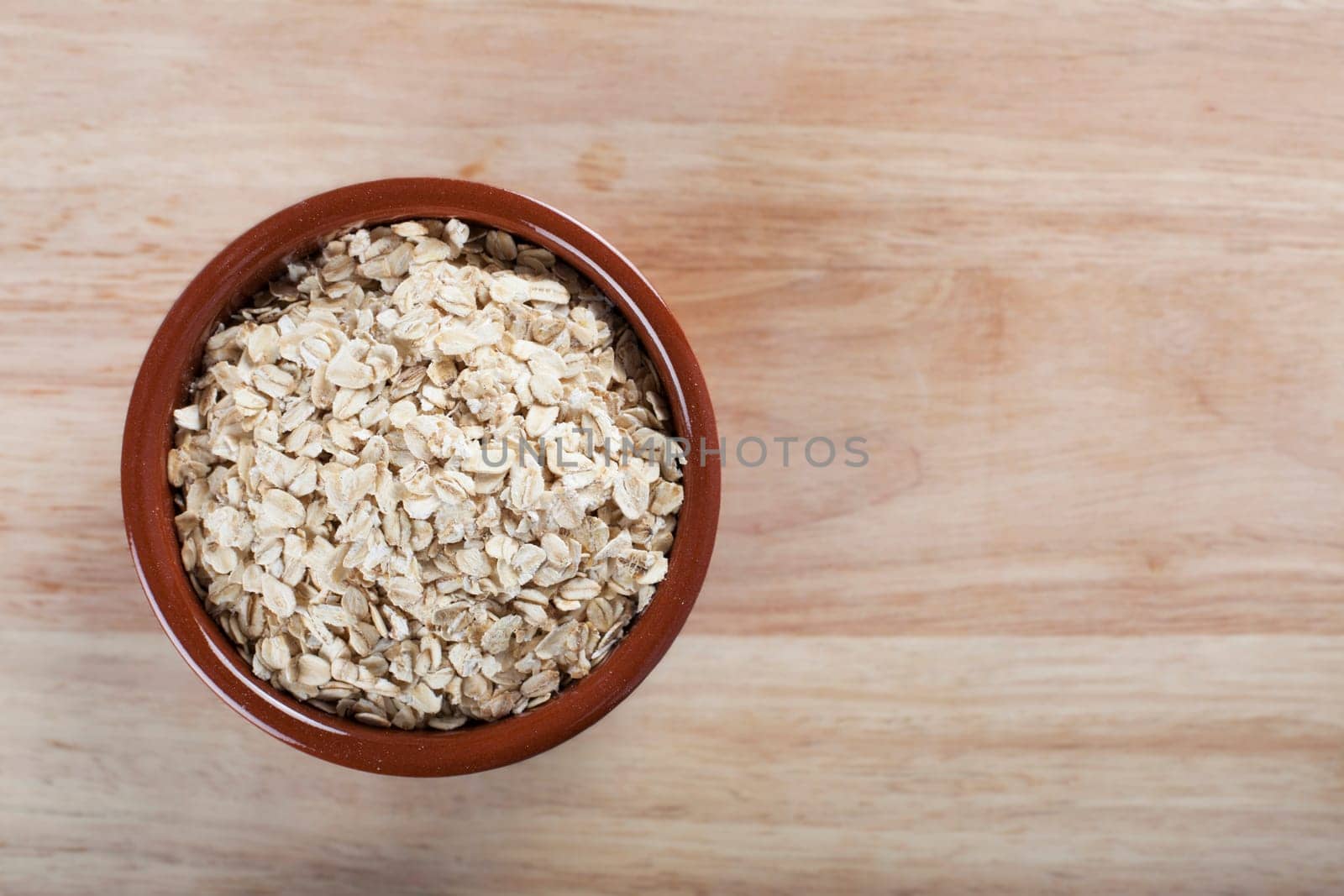 Bowl of rolled oats on wooden surface
