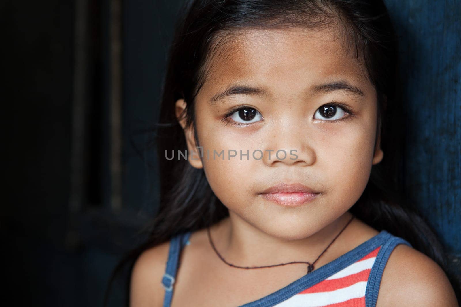 Asian child portrait - young girl from the Philippines against wall - natural light