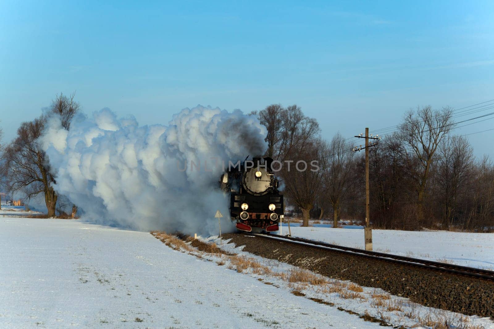 Vintage steam train puffing through countryside during wintertime