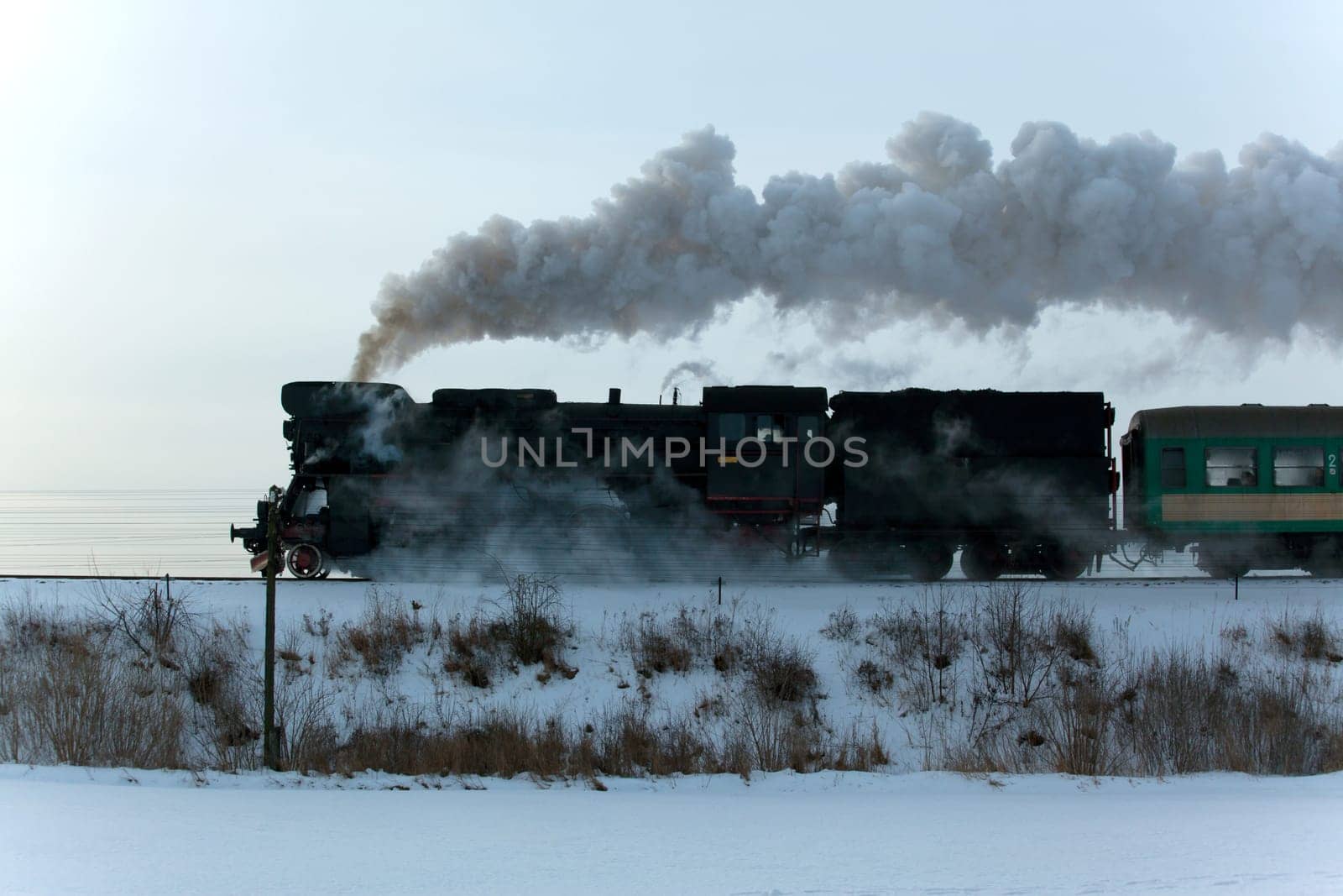Vintage steam train puffing through countryside during wintertime