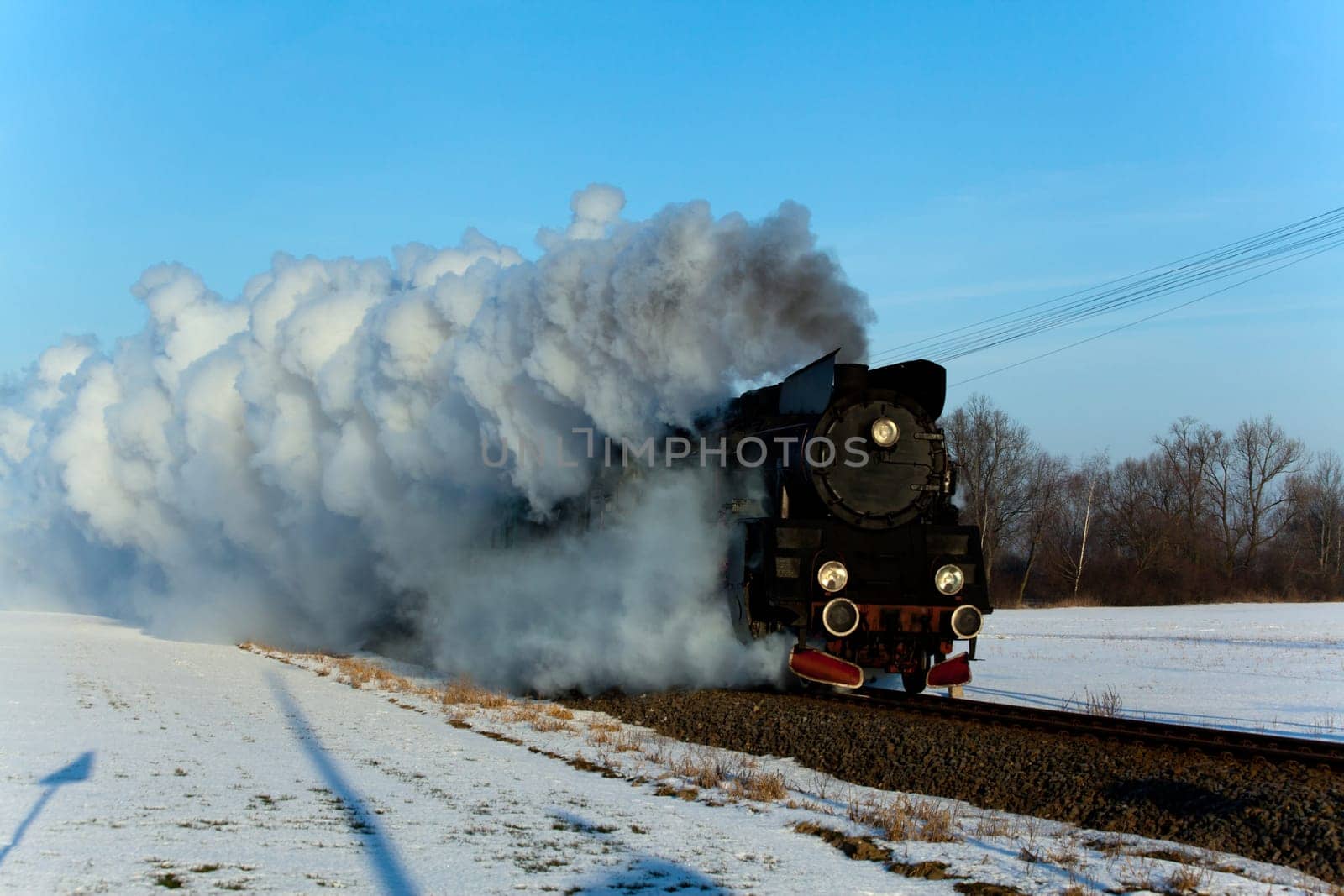 Vintage steam train puffing through countryside during wintertime