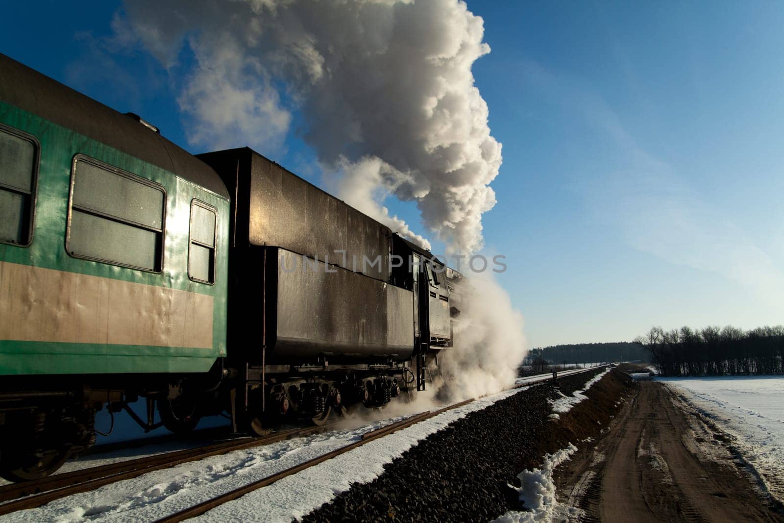 Vintage steam train puffing through countryside during wintertime