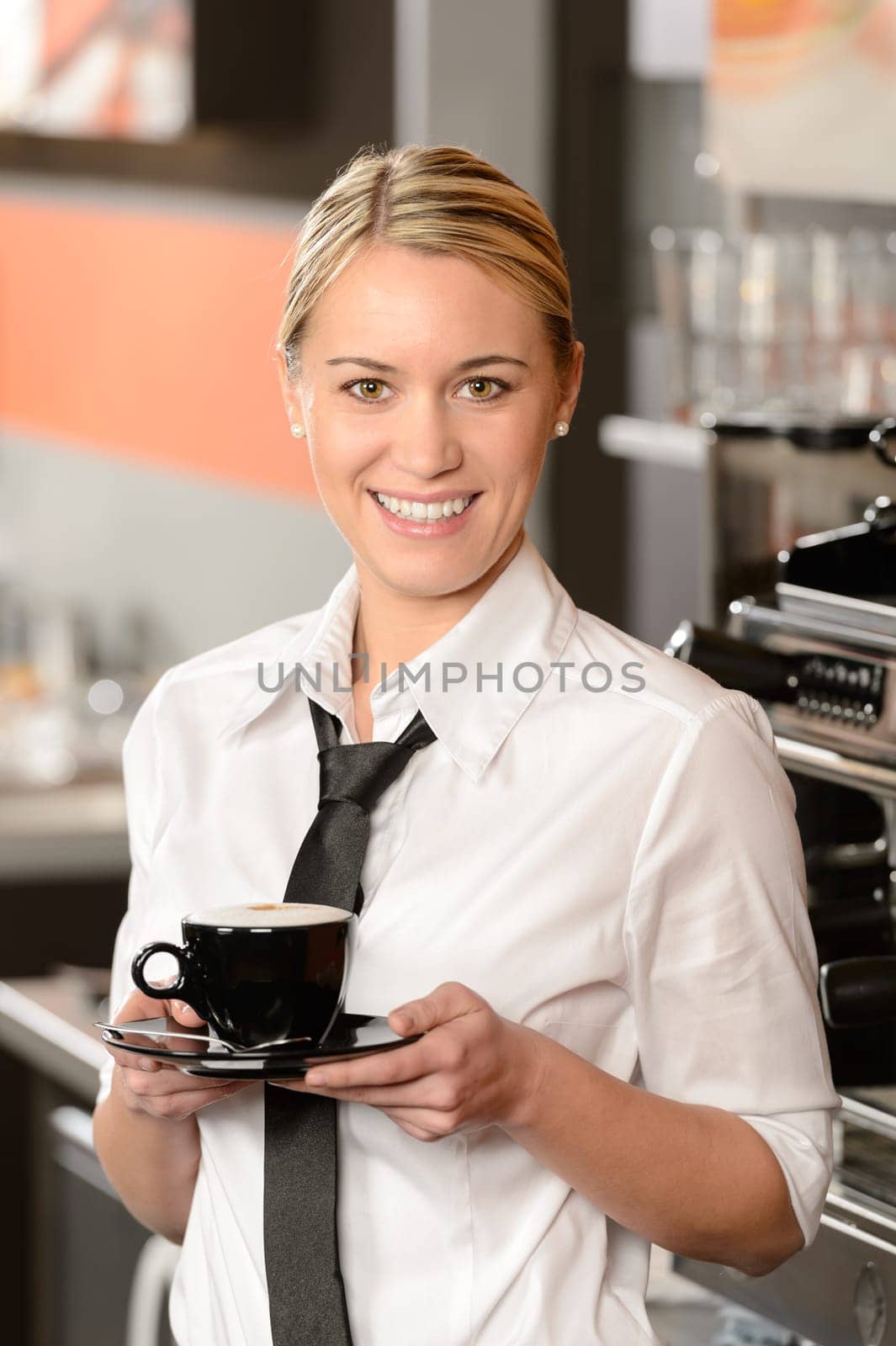 Young smiling waitress posing with cup of coffee