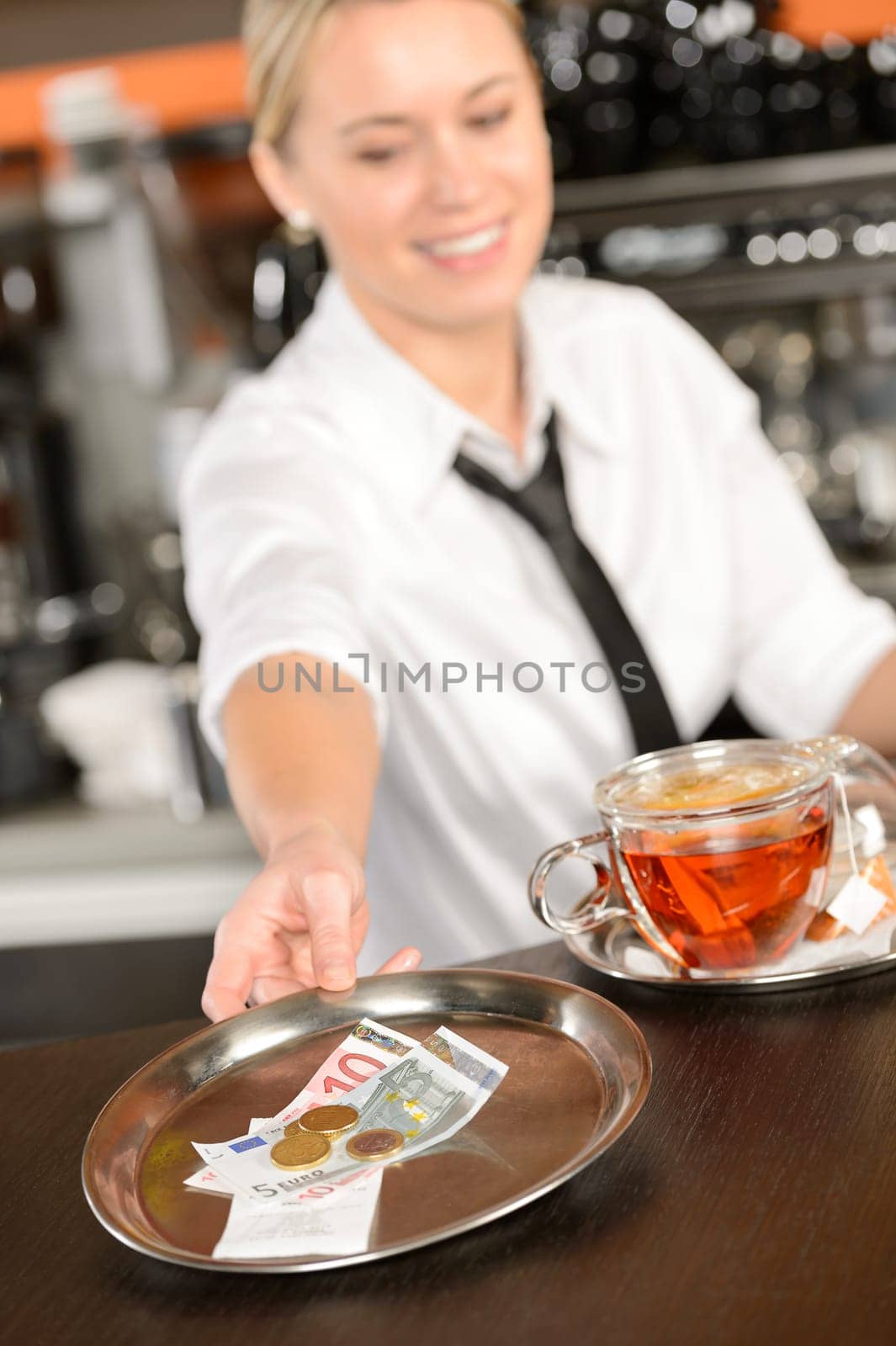 Attractive waitress taking tip in bar from tray euro
