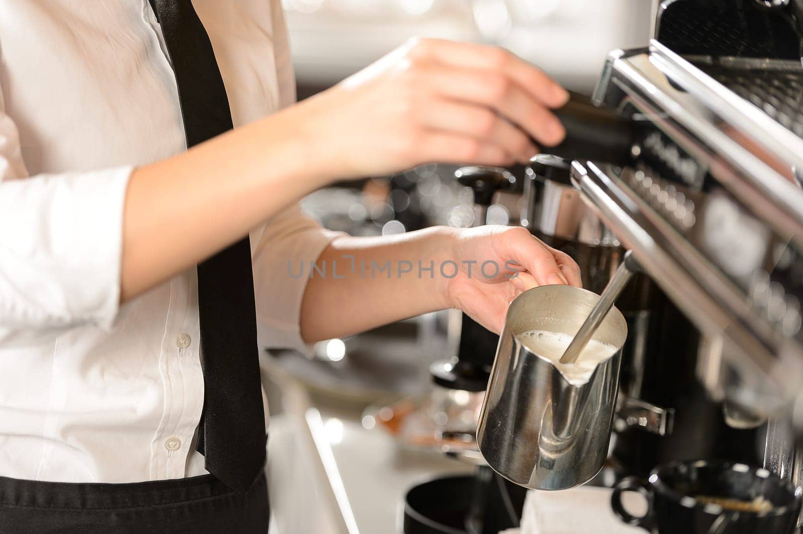 Barista steaming milk for hot cappuccino with machine