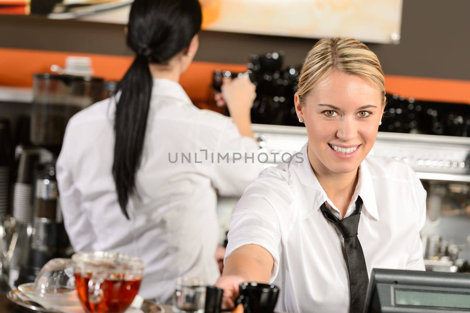 Young happy waitress cashier giving coffee in cafe