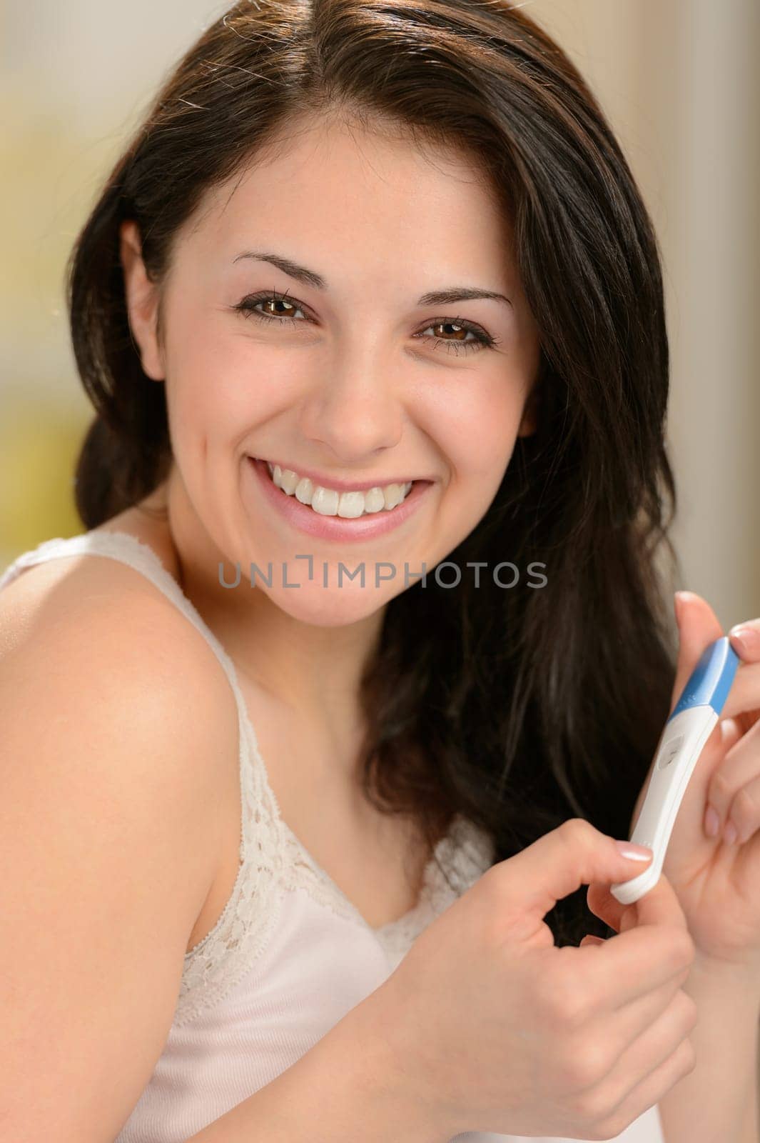 Portrait of cheerful young woman holding pregnancy test