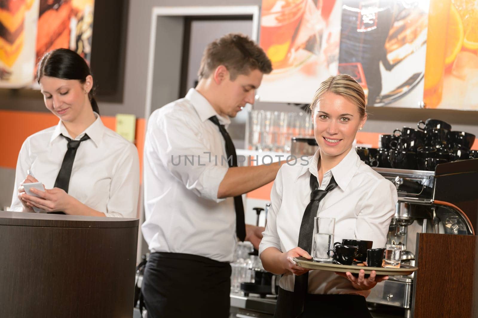 Confident waitresses and waiter working in bar serving drinks