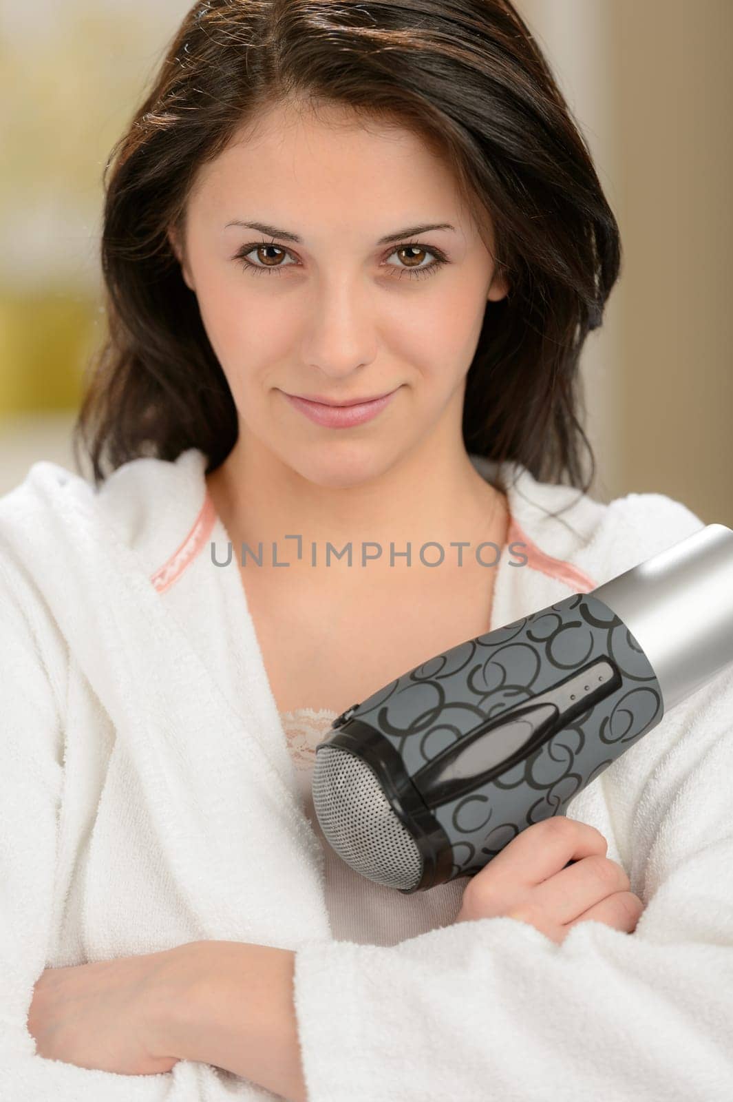 Confident girl posing with blow dryer in bathrobe