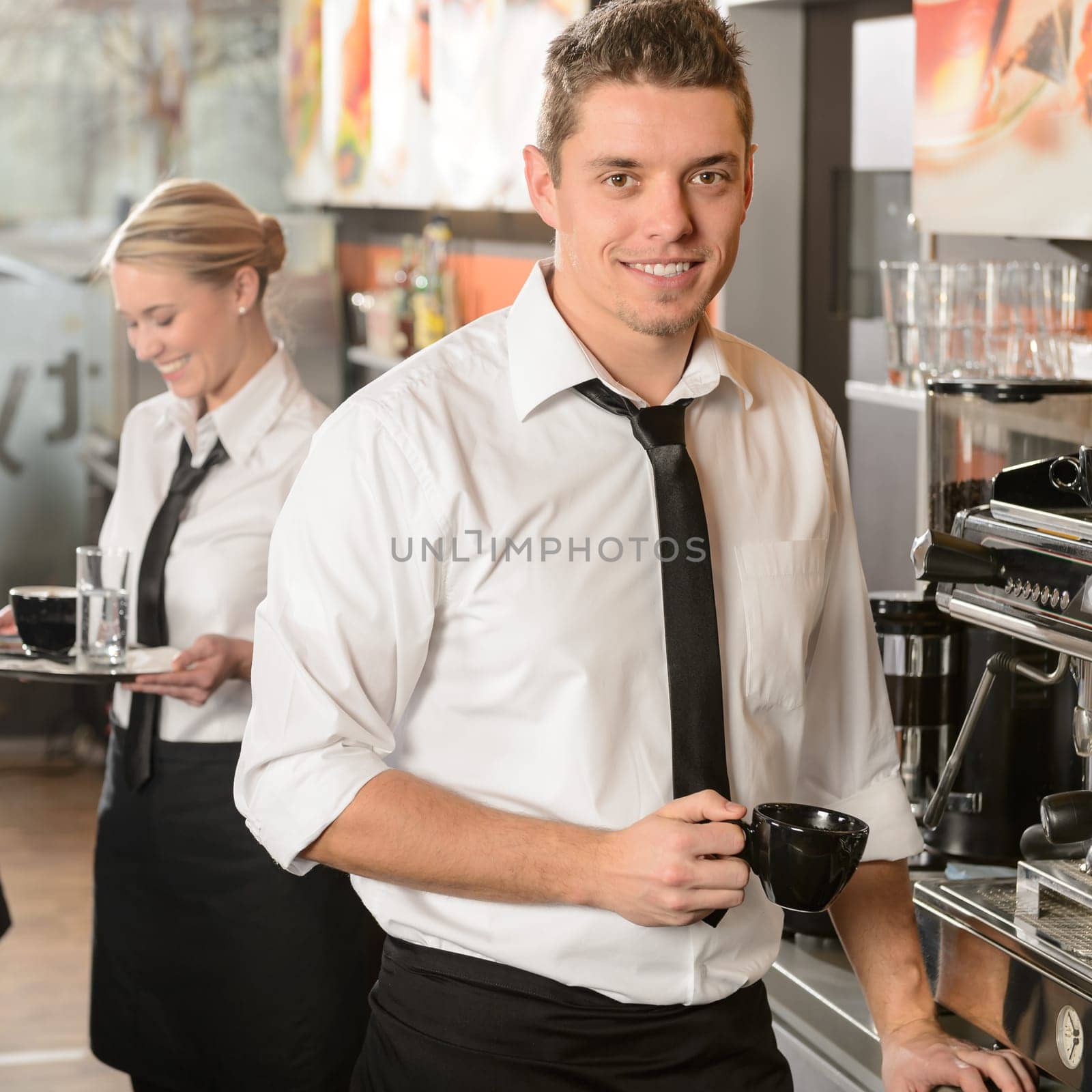 Handsome waiter making coffee with espresso machine in coffee house