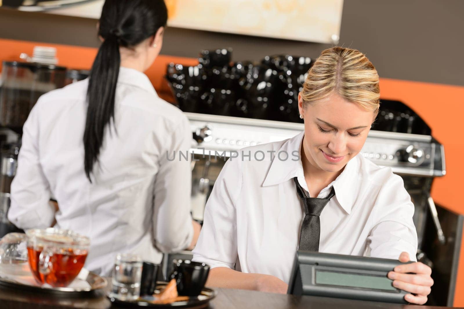Happy waitresses working at cafe in uniform