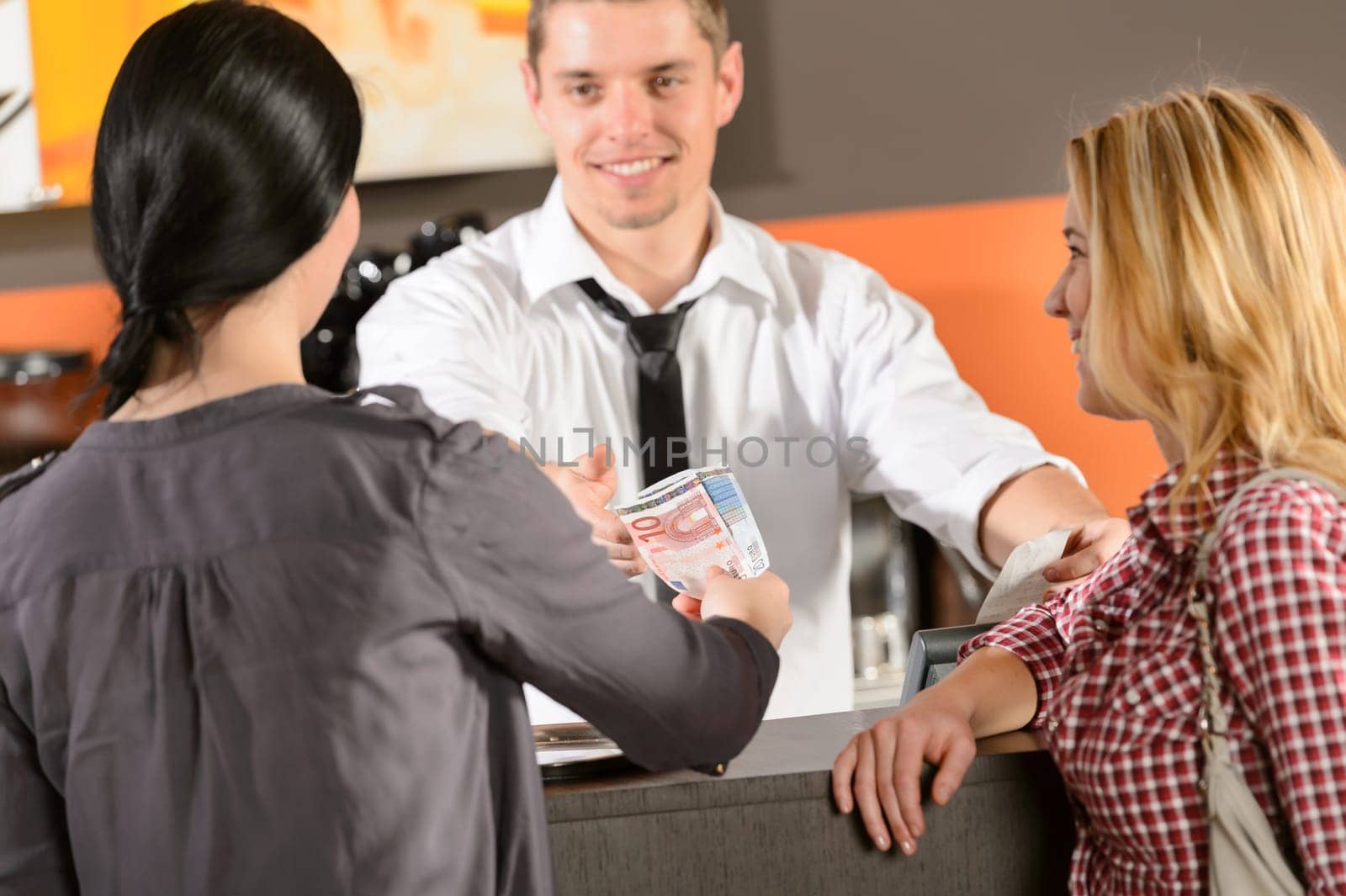 Female customers paying by cash euro in bar to bartender