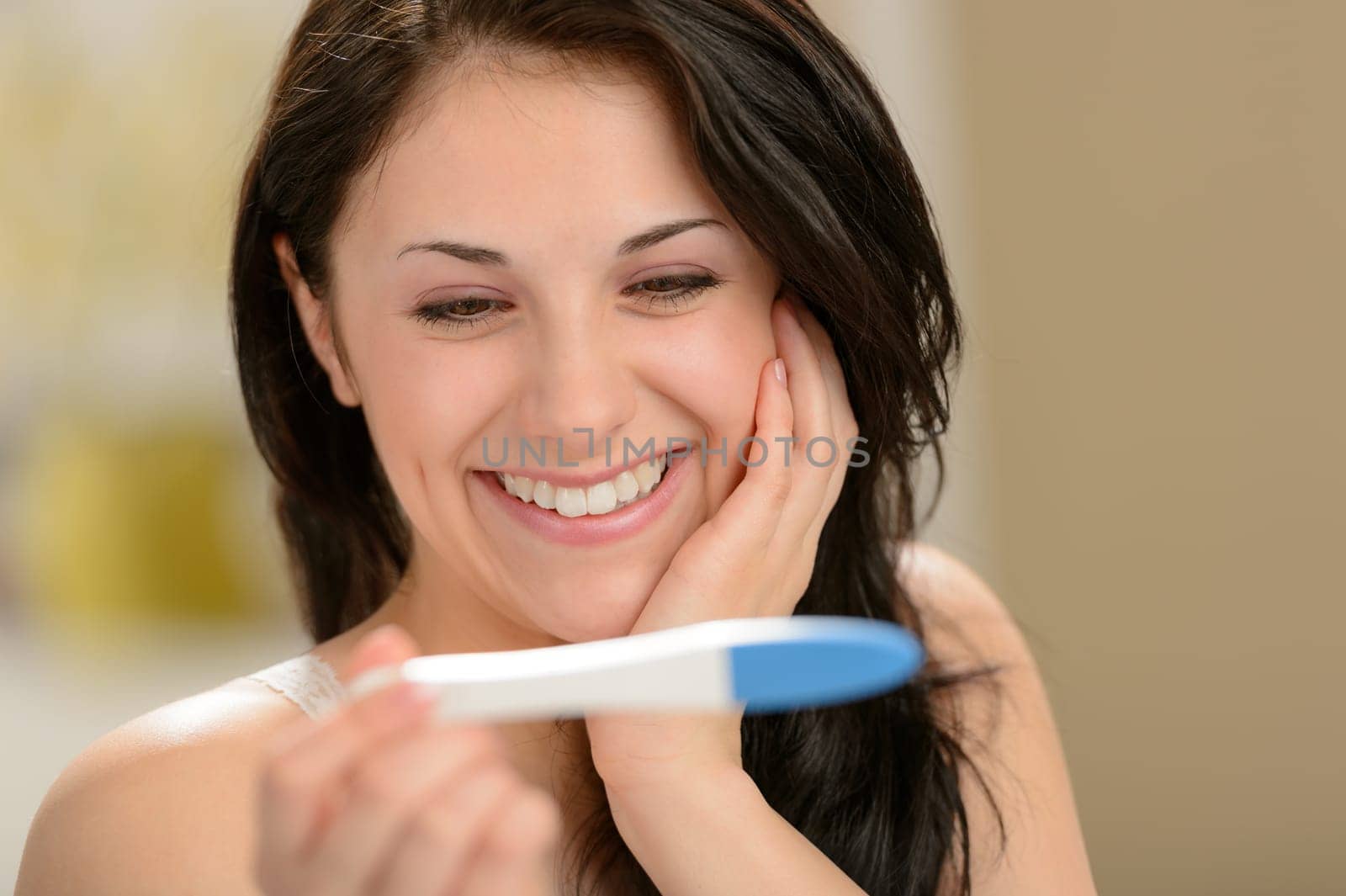 Delighted and surprised woman holding pregnancy test