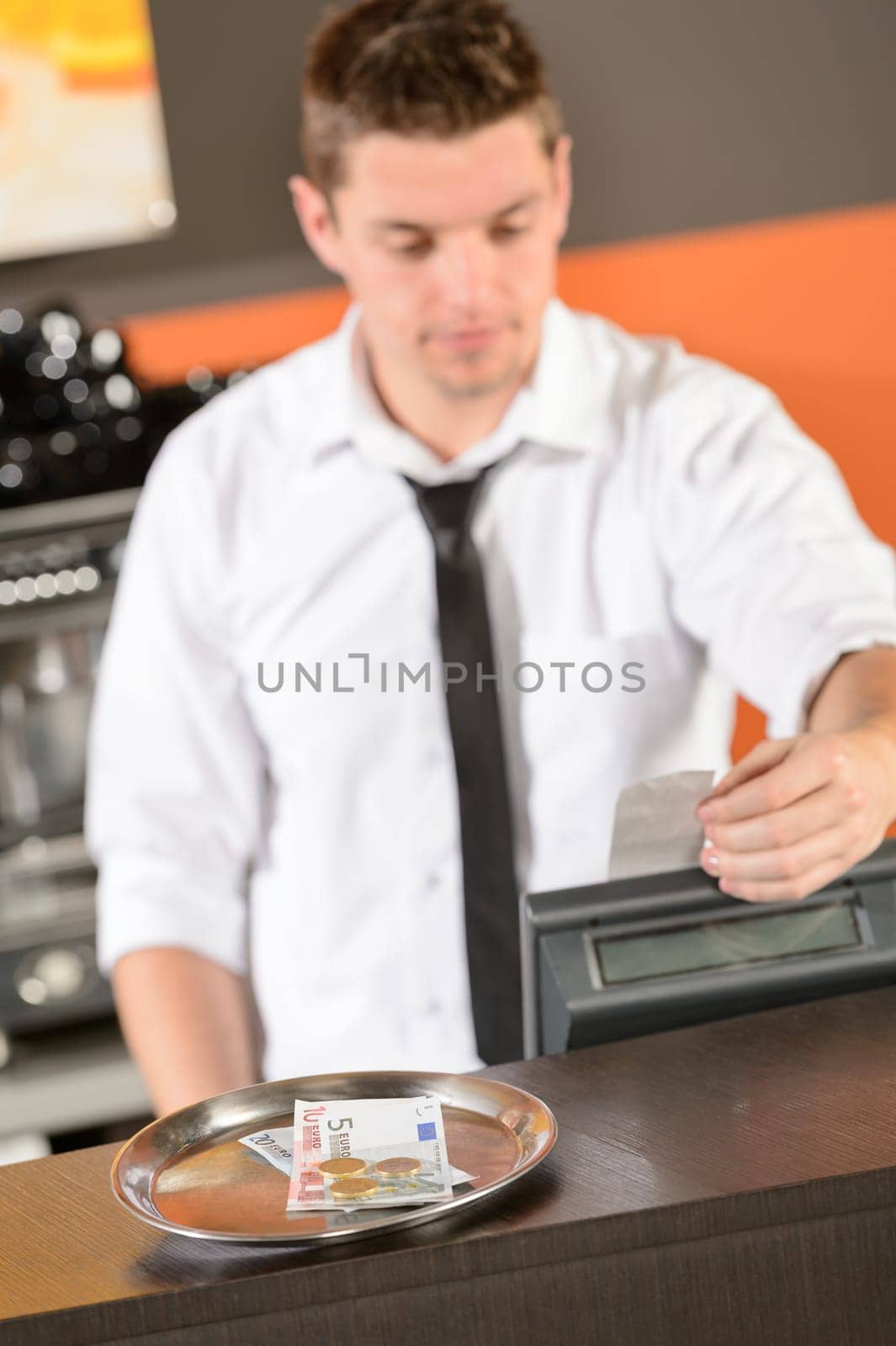 Young bartender in uniform taking cash EUR in bar