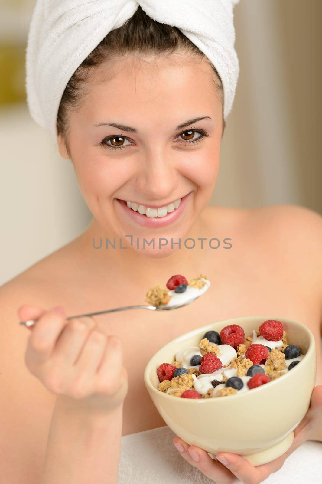 Joyful girl eating a bowl of muesli for breakfast