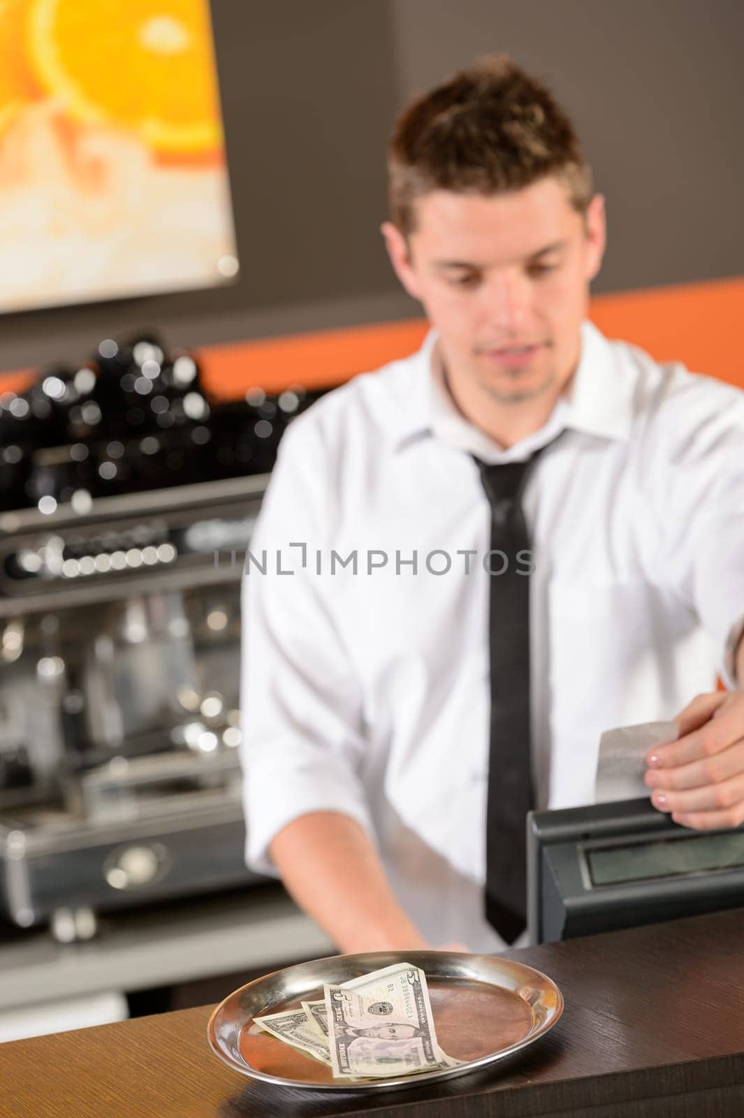Young bartender in uniform taking cash USD in bar
