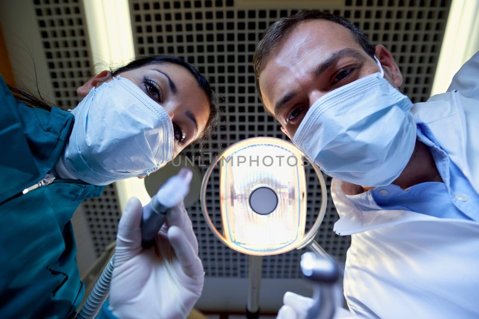Medical personnel and staff at work in dental clinic, dentist and assistant working with customer. Low angle