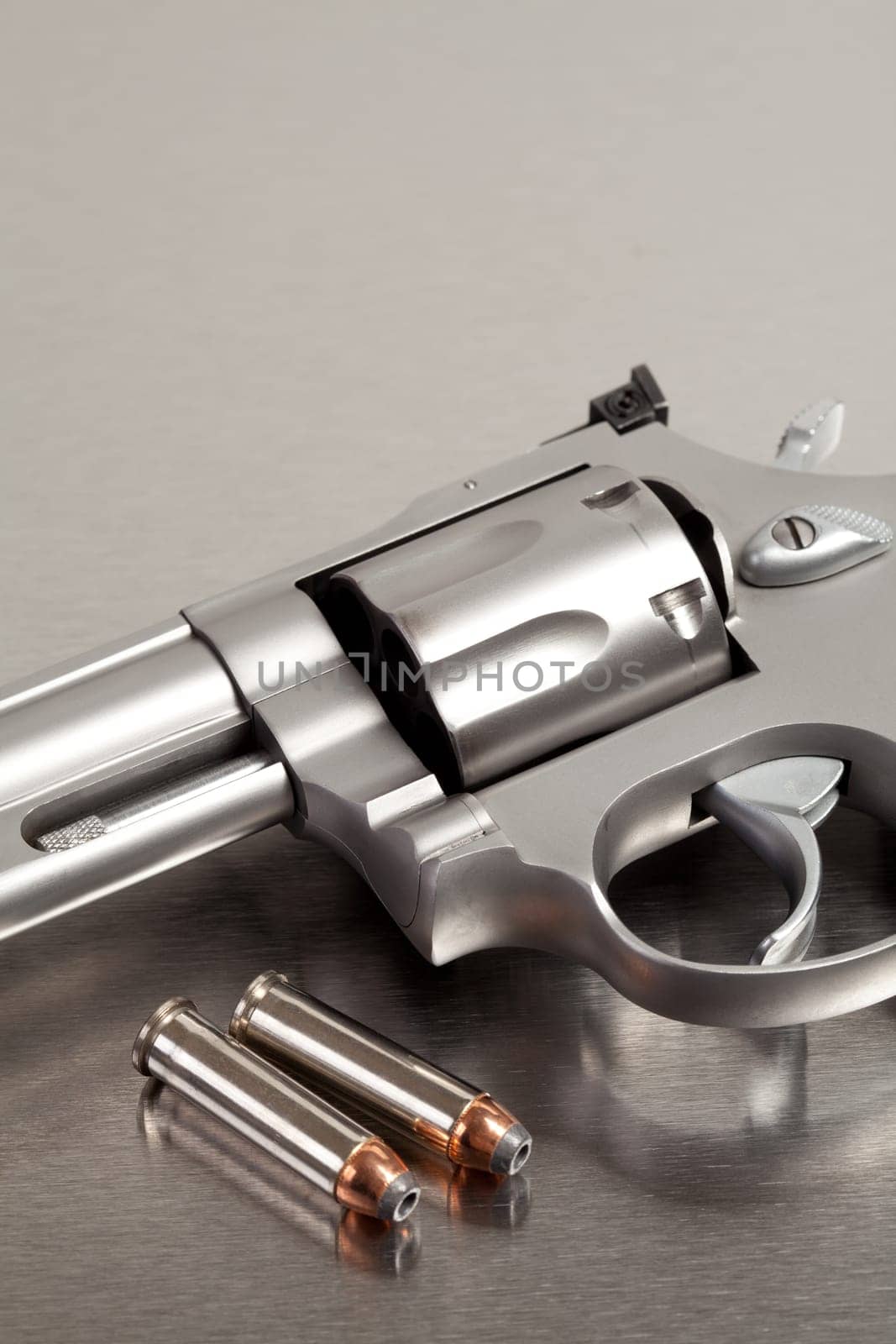 Handgun with bullets - modern revolver on brushed metal with two bullets