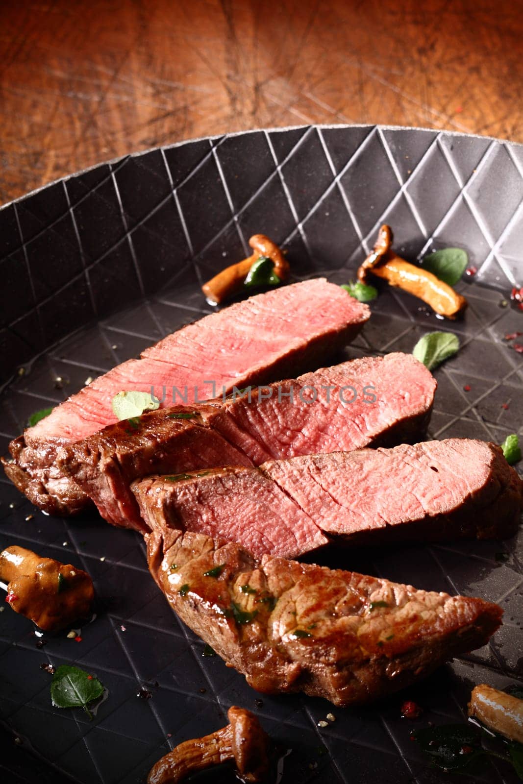 Sliced grilled lean beef steak in a pan cooked to a delicious pink medium rare consistency waiting to be served in a gourmet meal
