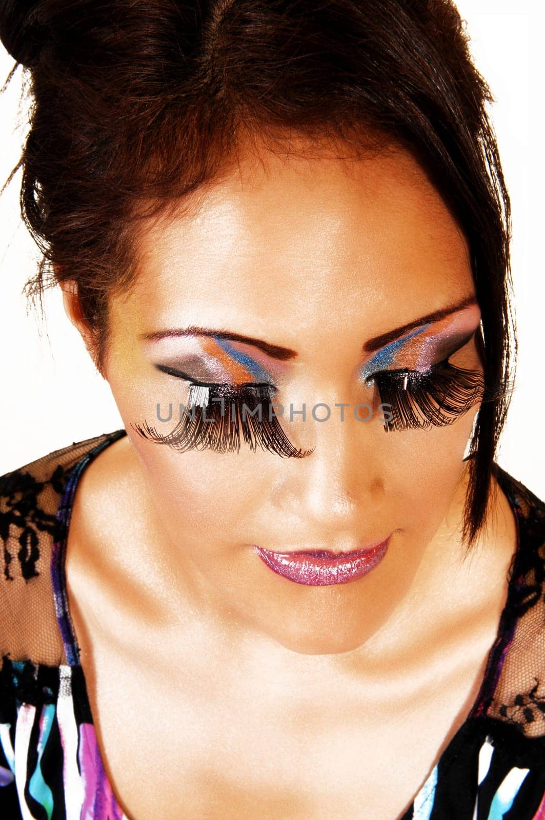 A very pretty face of a young woman with lovely makeup and long eyelashes and red lips in a closeup shoot with her eyes closed.