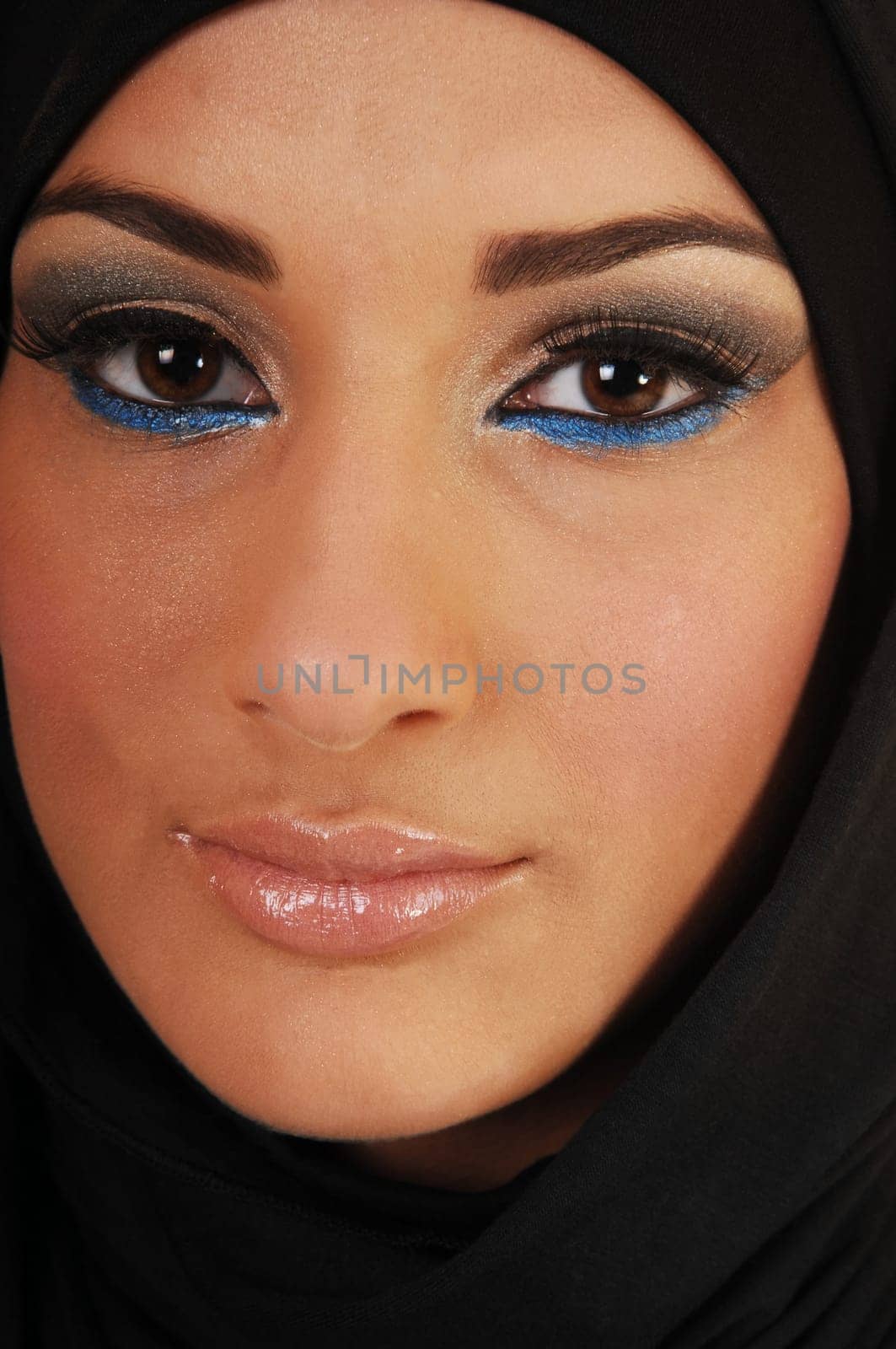 A pretty and young teen girl with a black headscarf and nice makeup looking into the camera in closeup, for white background.